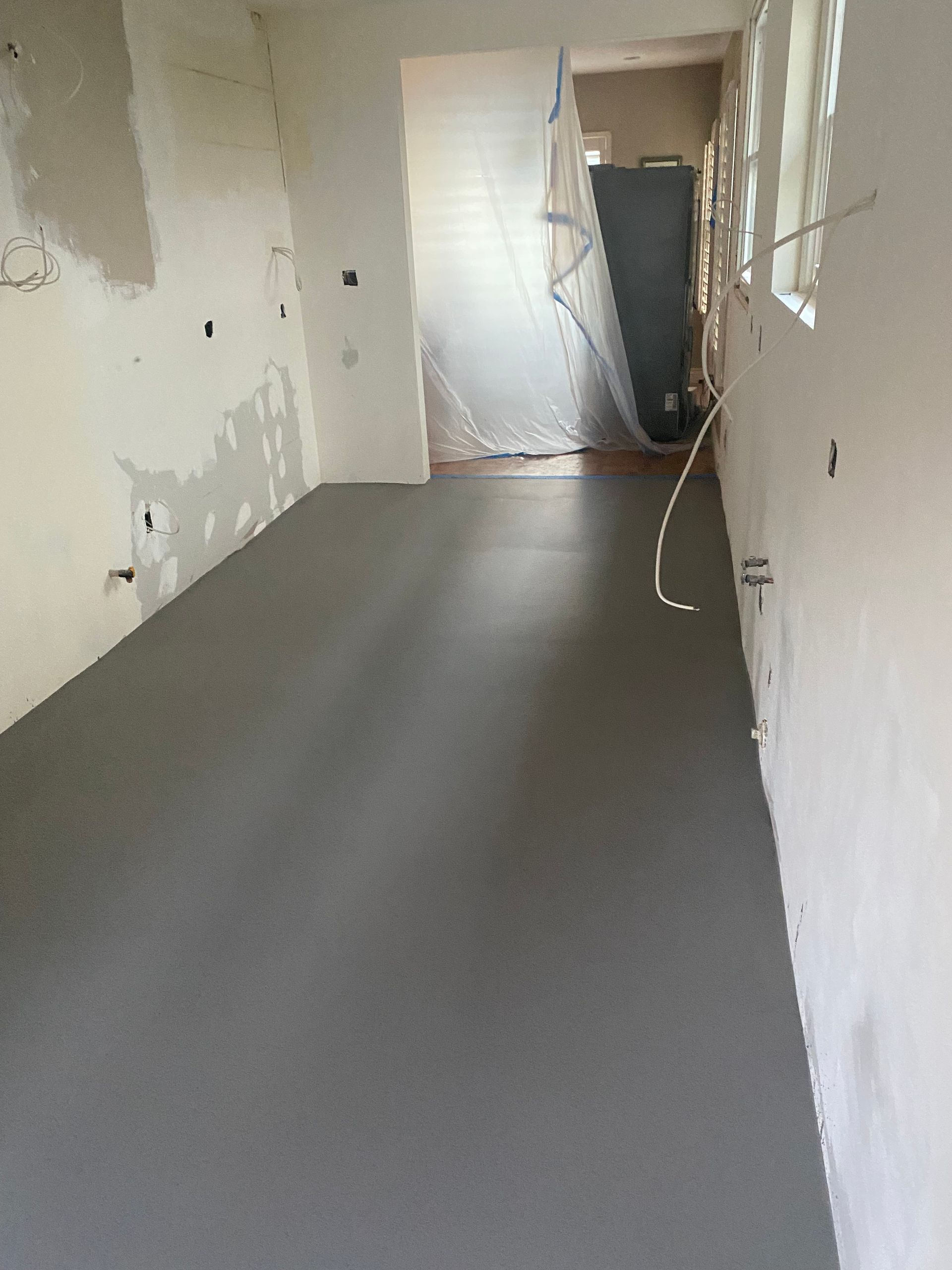 An empty room with a gray floor and white walls.