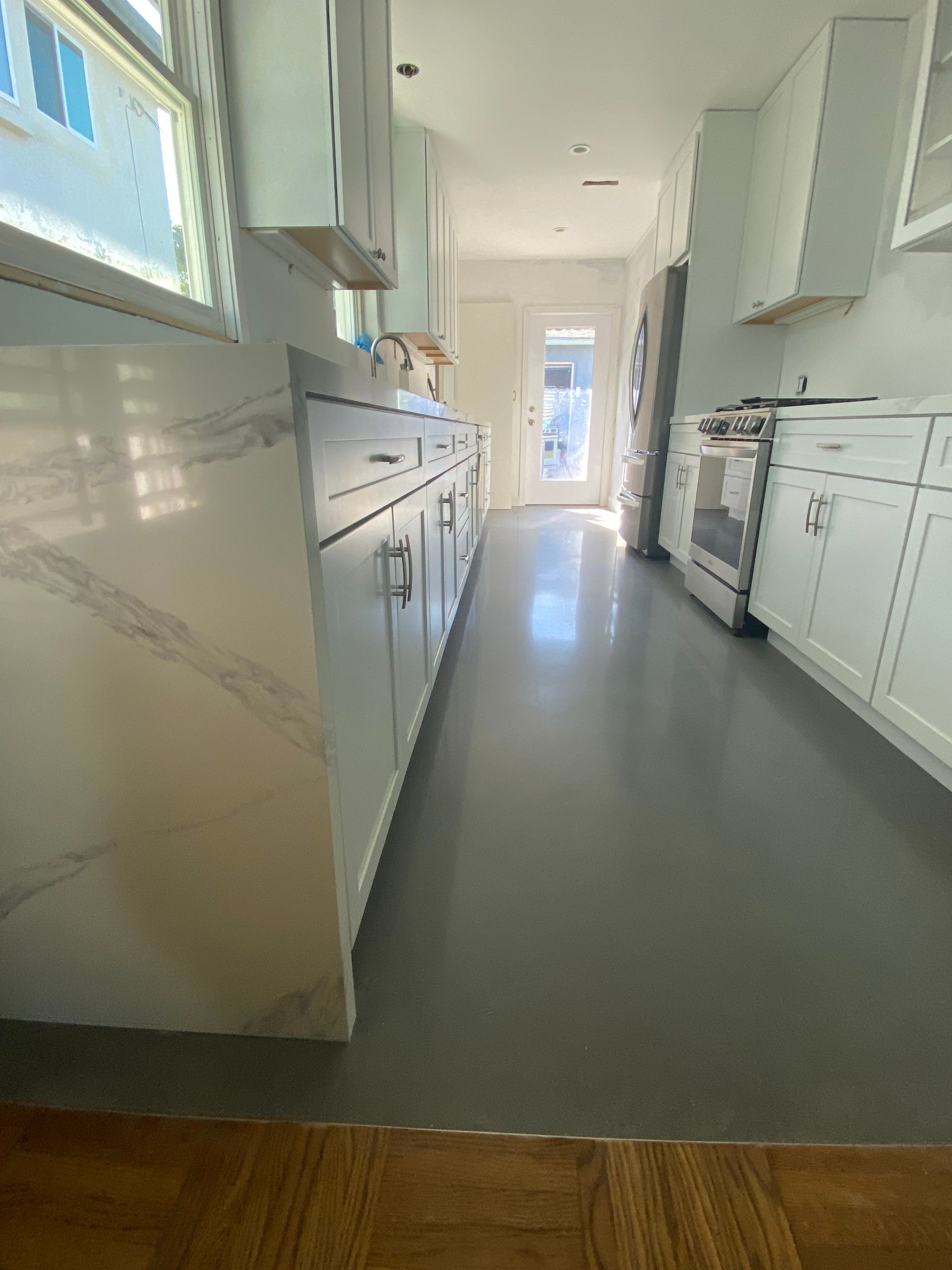 A kitchen with white cabinets and a gray floor.