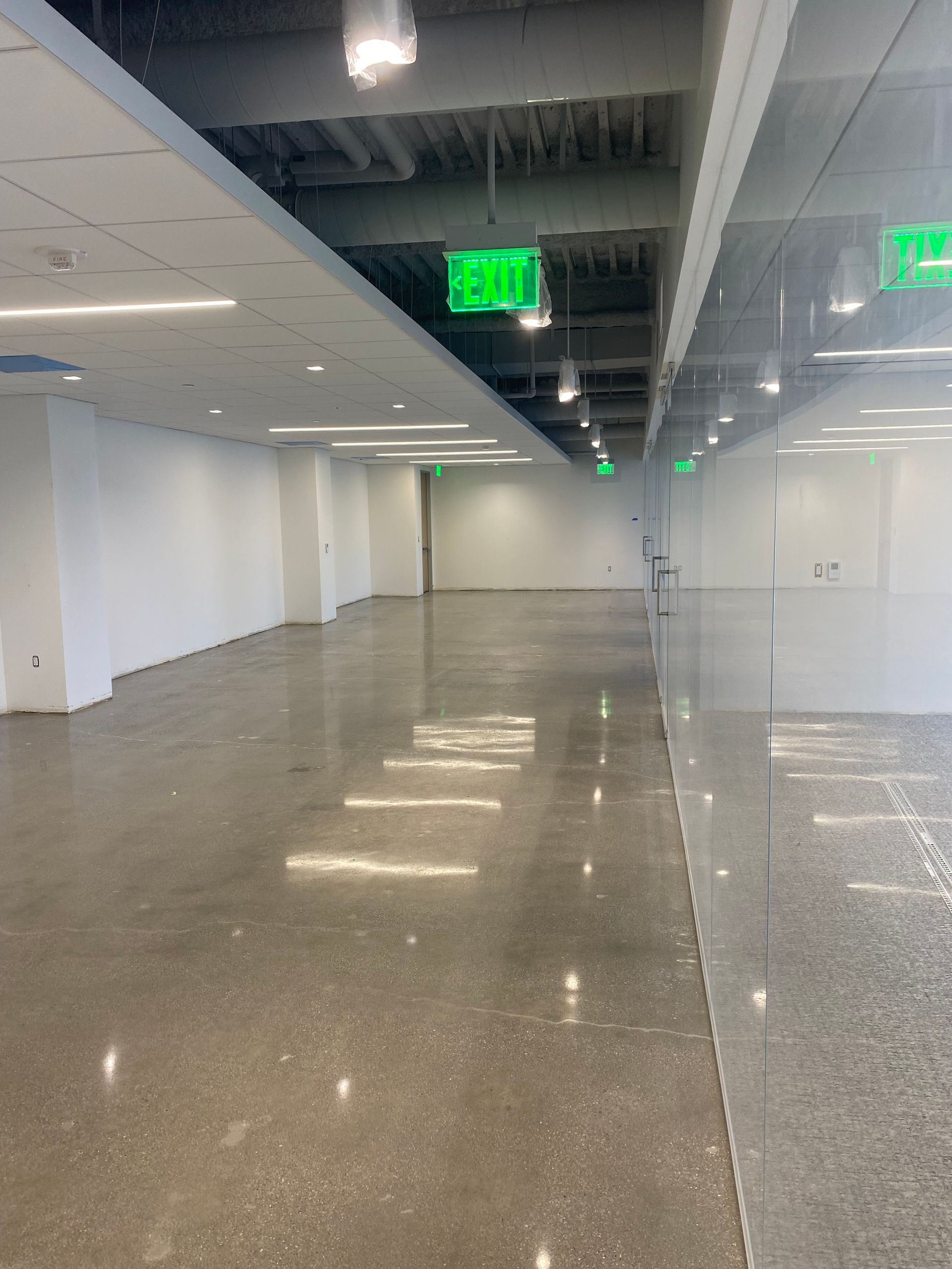 An empty hallway with a green exit sign on the ceiling