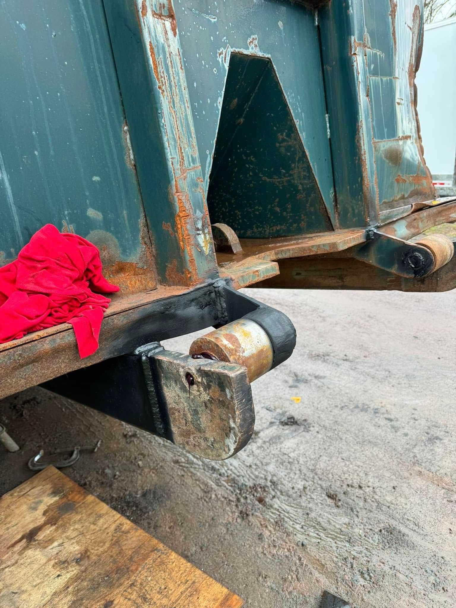 Rusty green industrial trash bin with a red glove on the side.