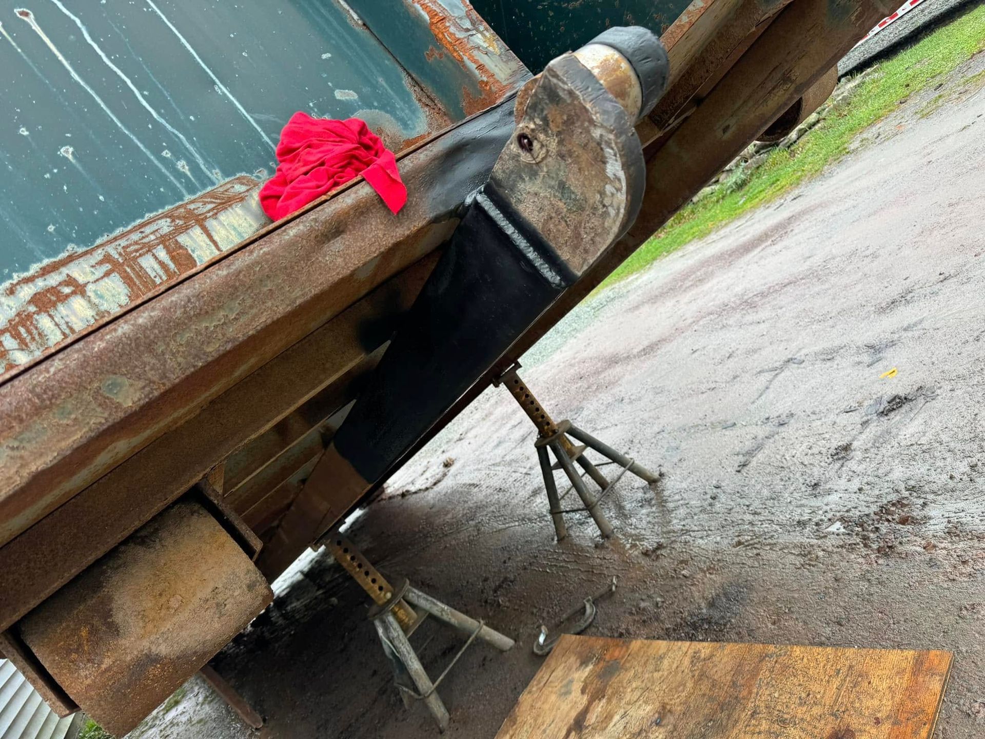 Metal frame supported by jacks; a section is freshly welded. Red cloth rests on top.