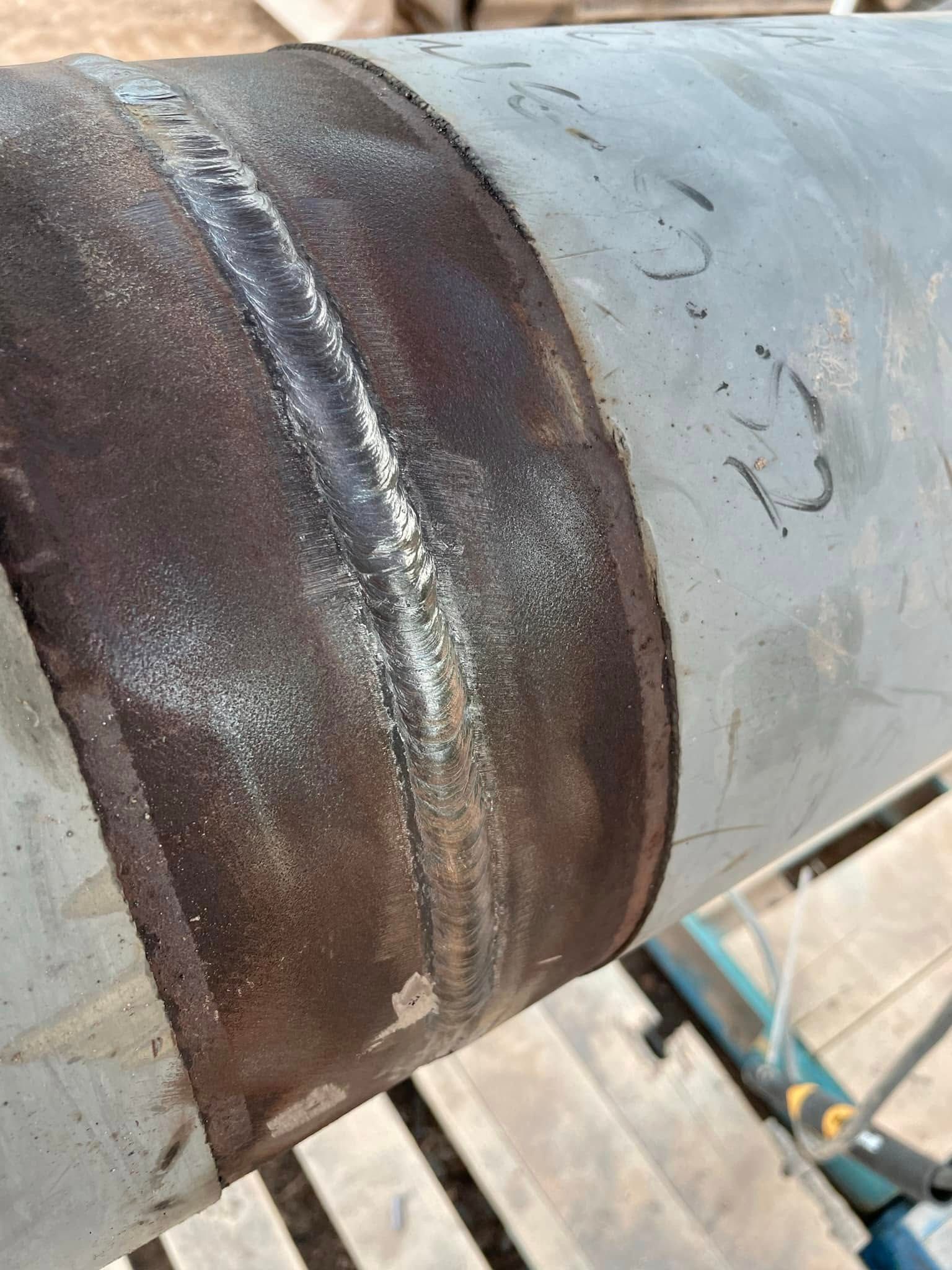 Welded metal pipe joint, showing weld bead and discoloration.
