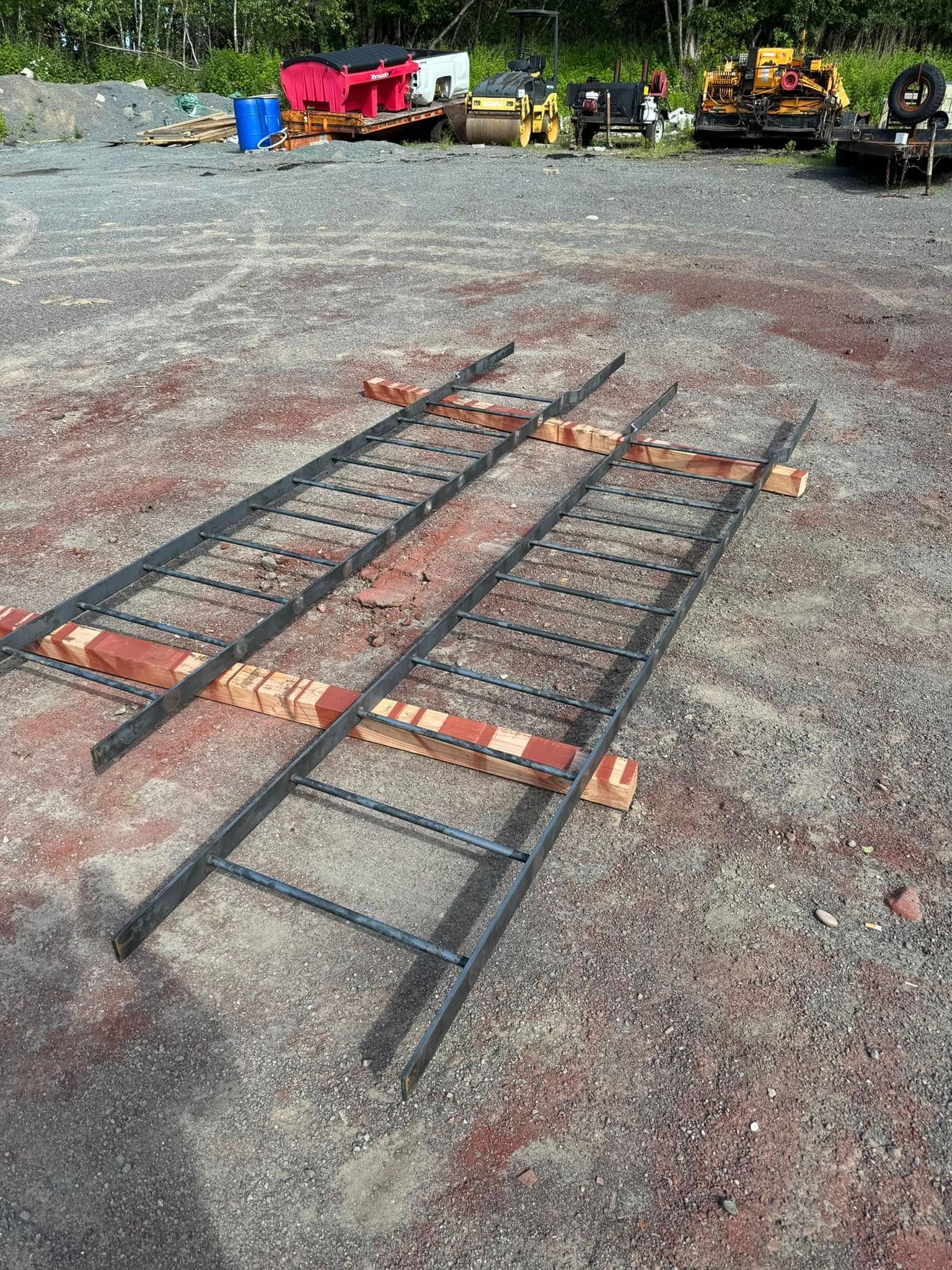 Two metal ladders on bricks in a gravel area, construction site in background.