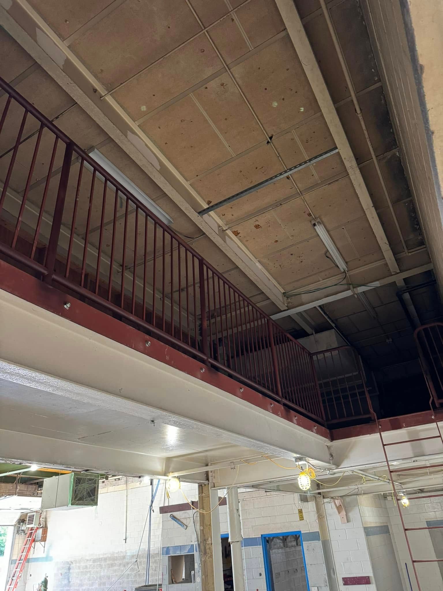 Interior shot of building under renovation; second-floor railing, exposed ceiling, unfinished walls.