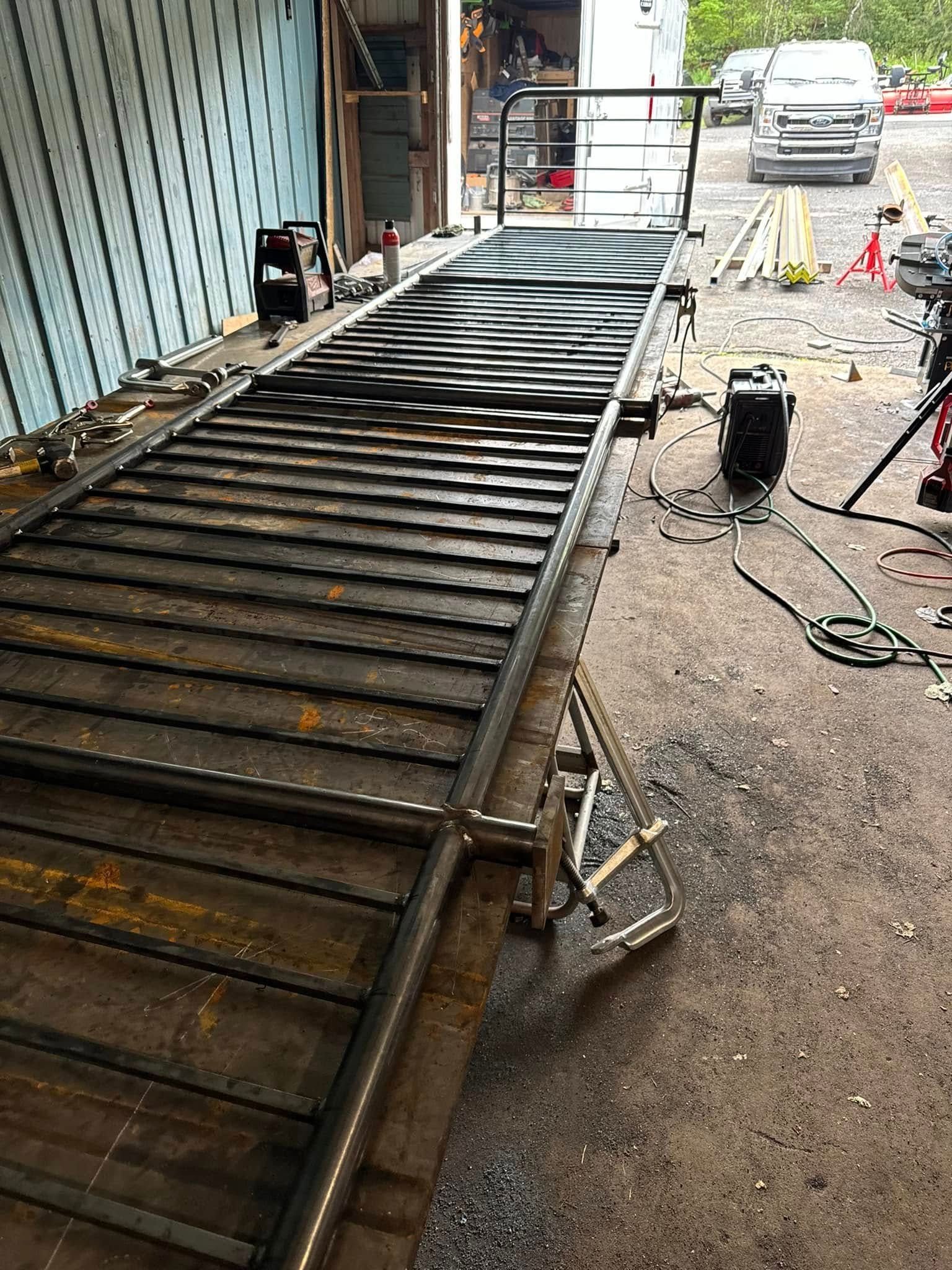 Metal ramp under construction outdoors; welding equipment nearby.