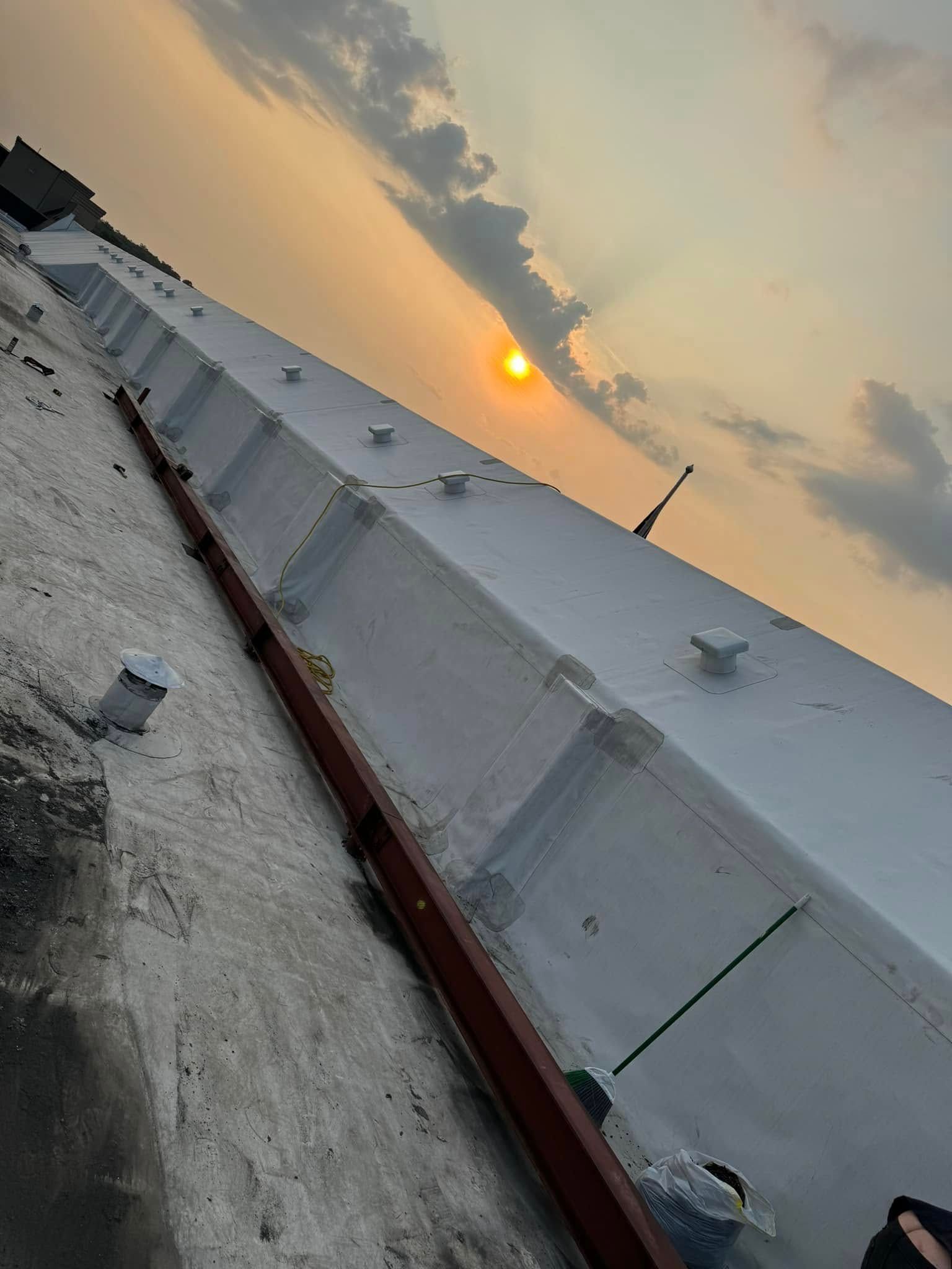 Sunset over a white structure on a rooftop.
