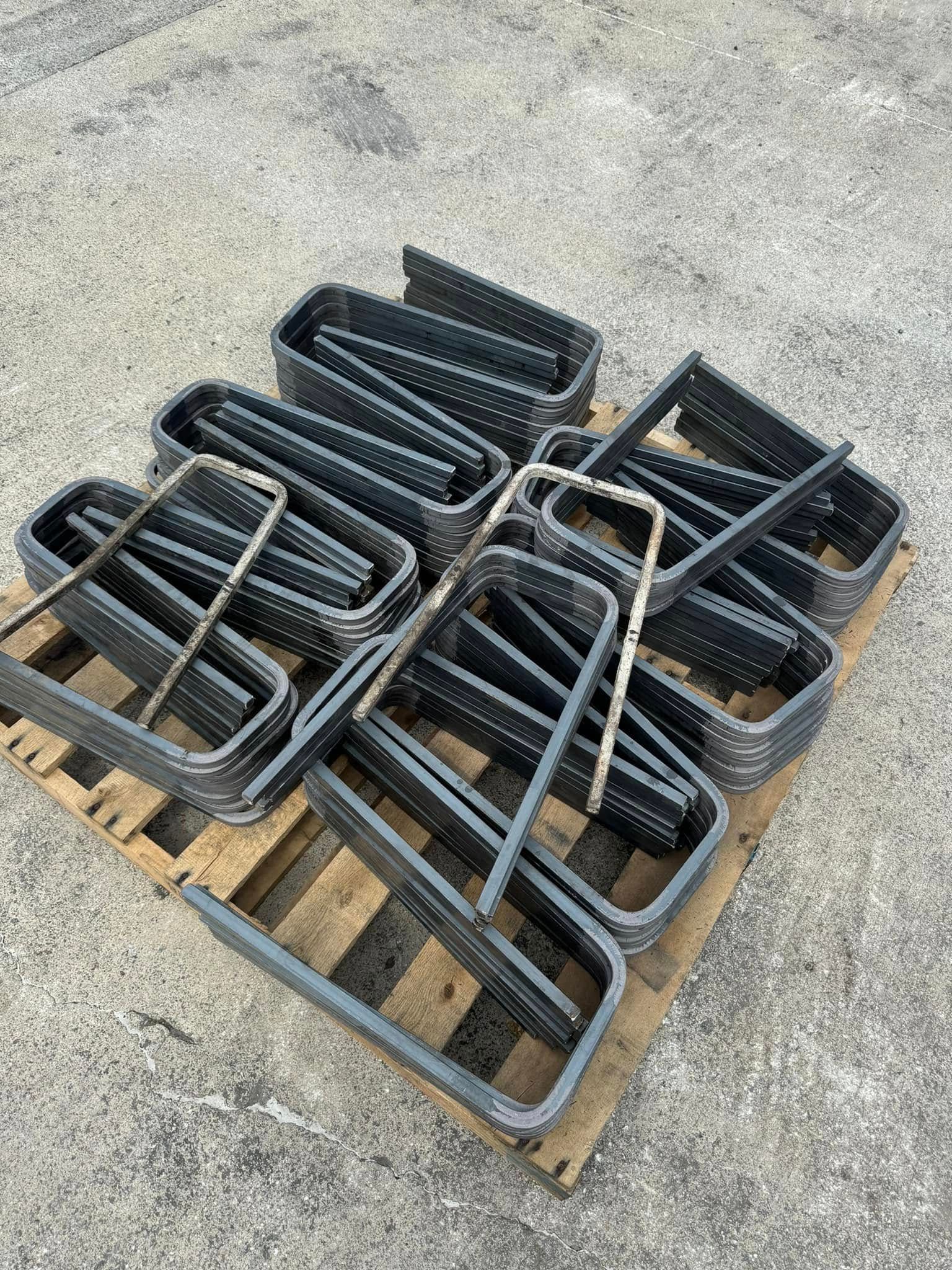 Black, metal, rectangular frames stacked on a wooden pallet, outside.