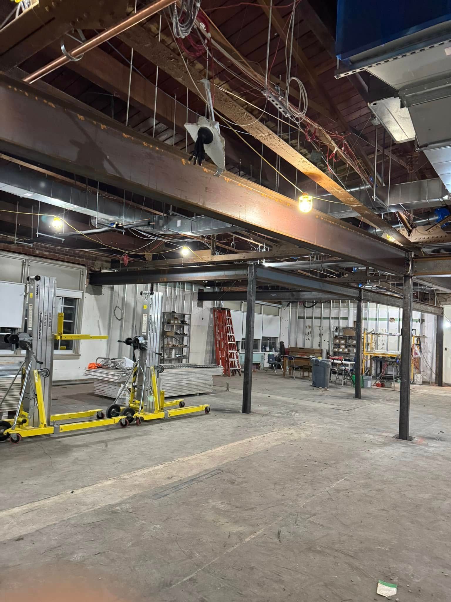 Construction site: steel beams support a new floor.  Workers in a room with exposed ceiling elements.