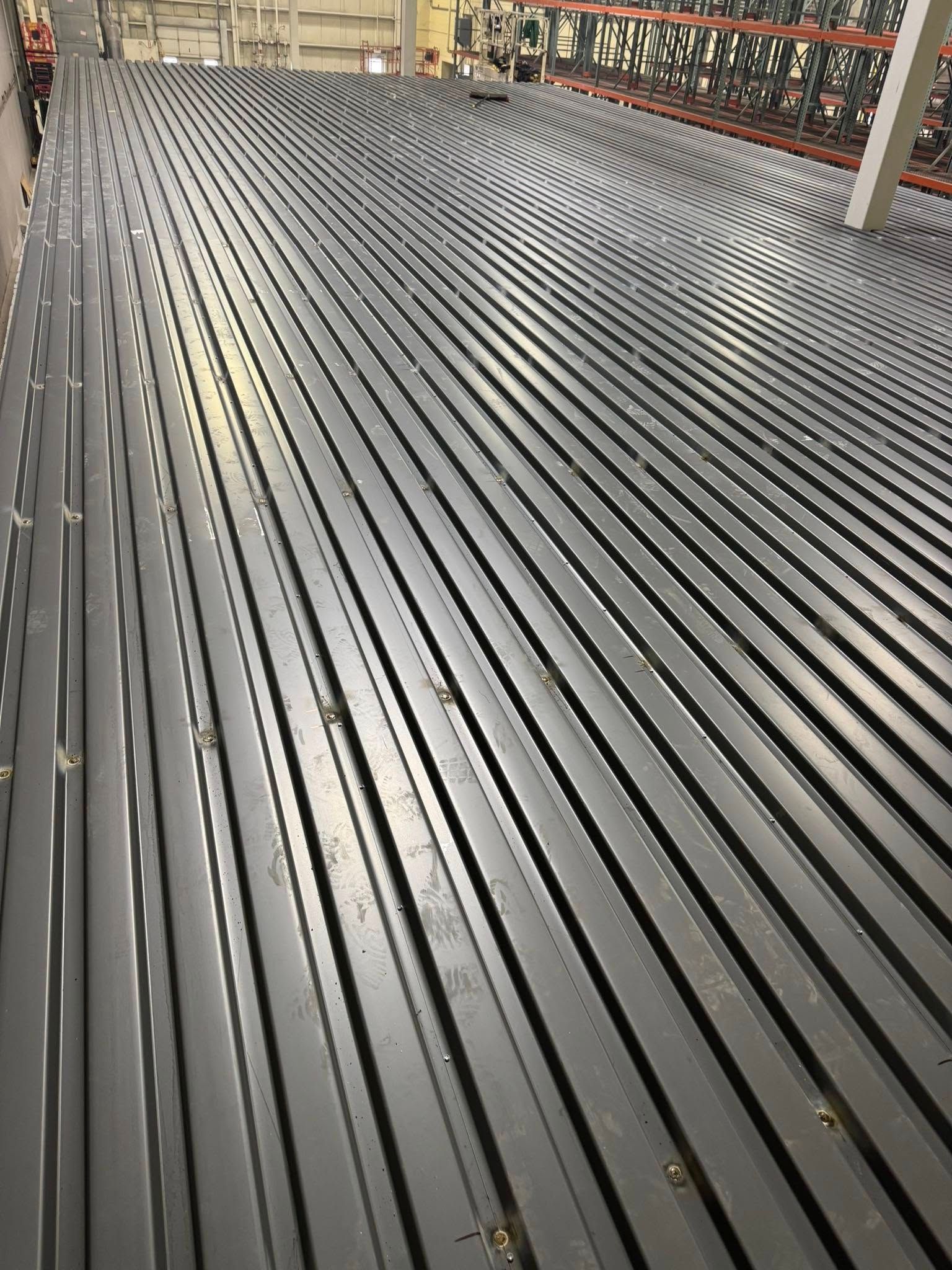 Gray metal corrugated flooring in a warehouse, creating a textured surface.