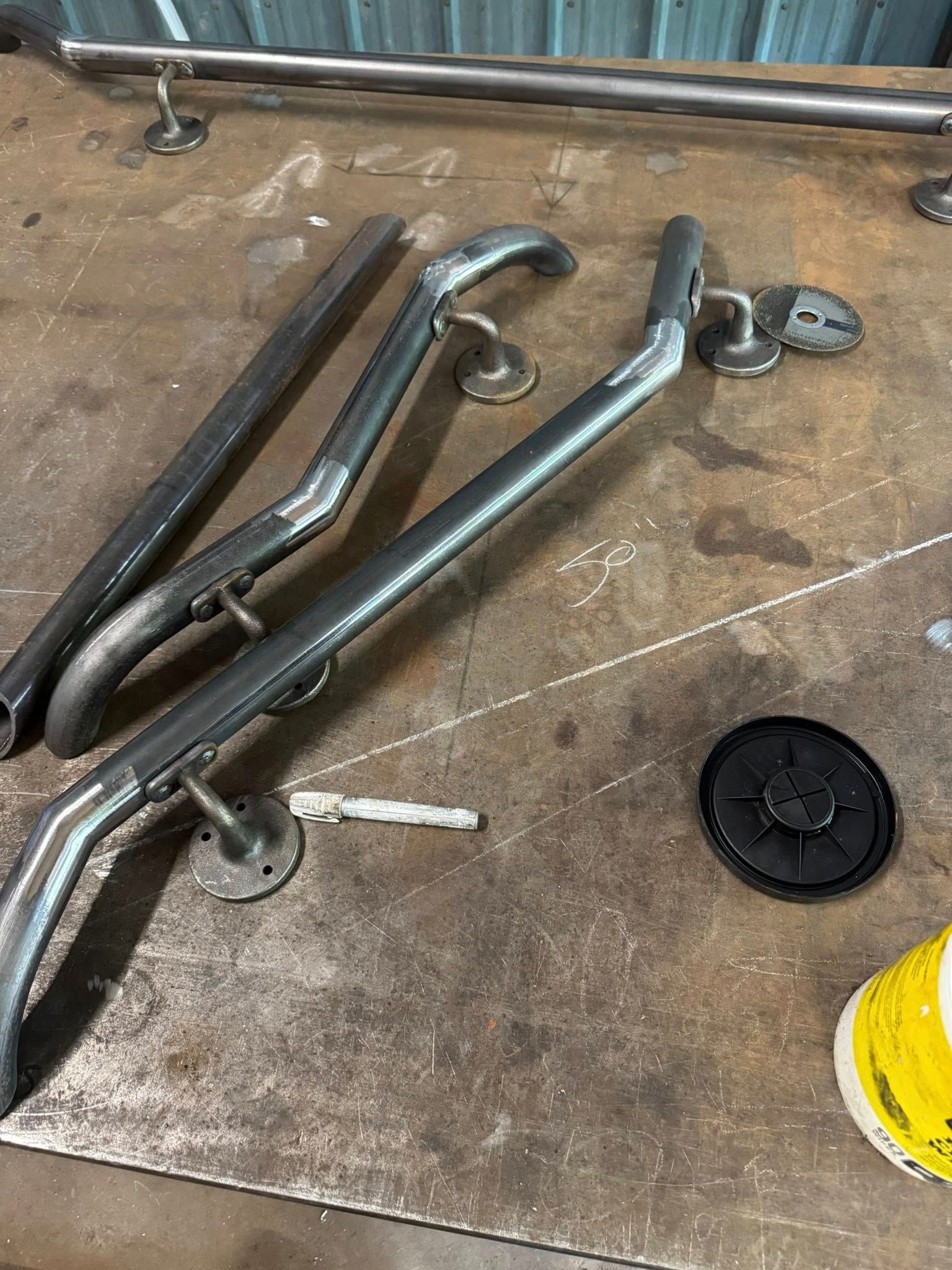 Metal handrails, pre-fabbed on a metal surface. Components are silver, with round black and silver attachments.