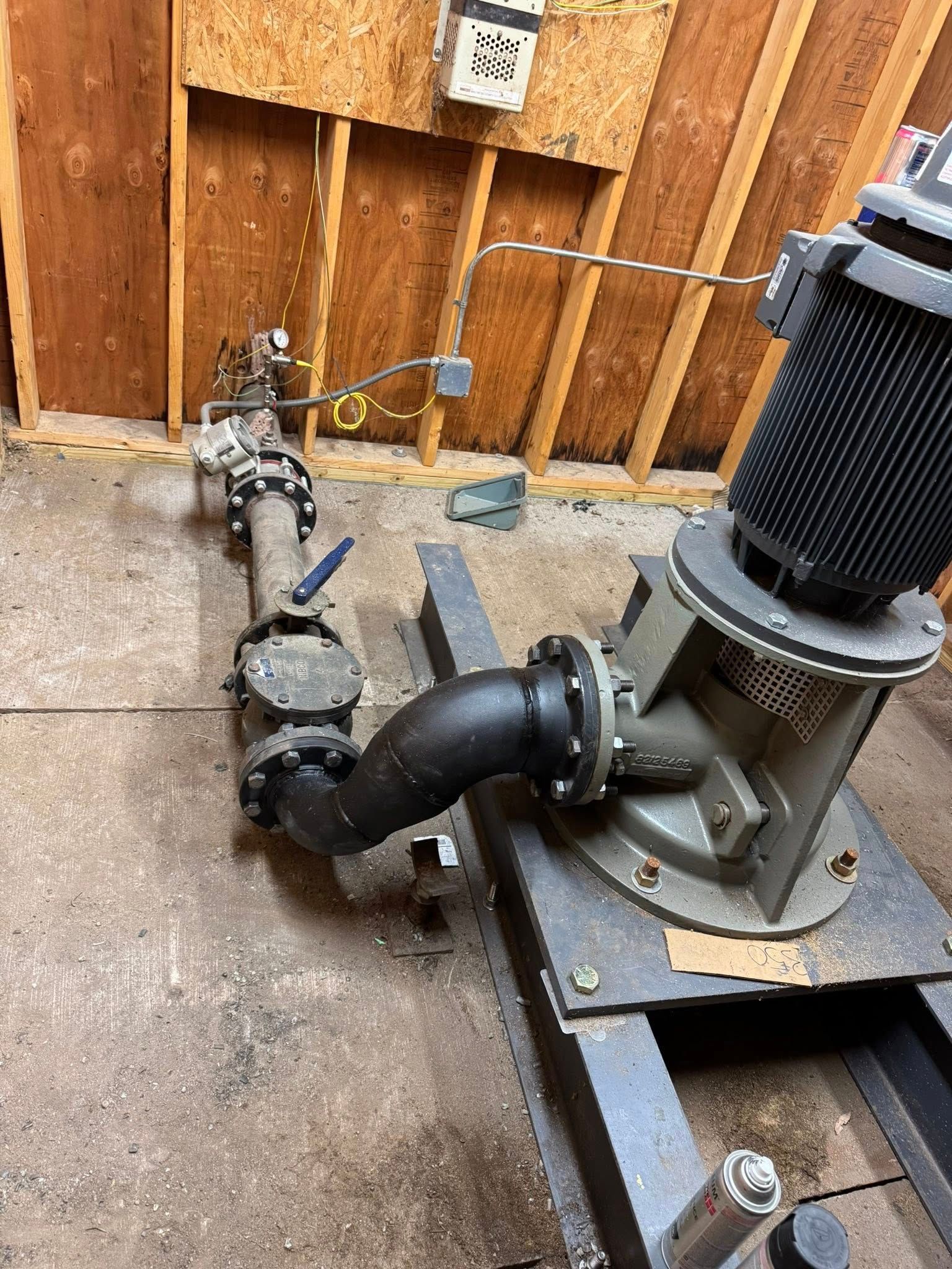 Industrial water pump system with pipes and valves, mounted on a metal frame, indoors.