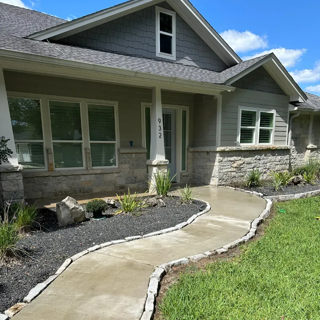 There is a concrete walkway leading to the front of the house.