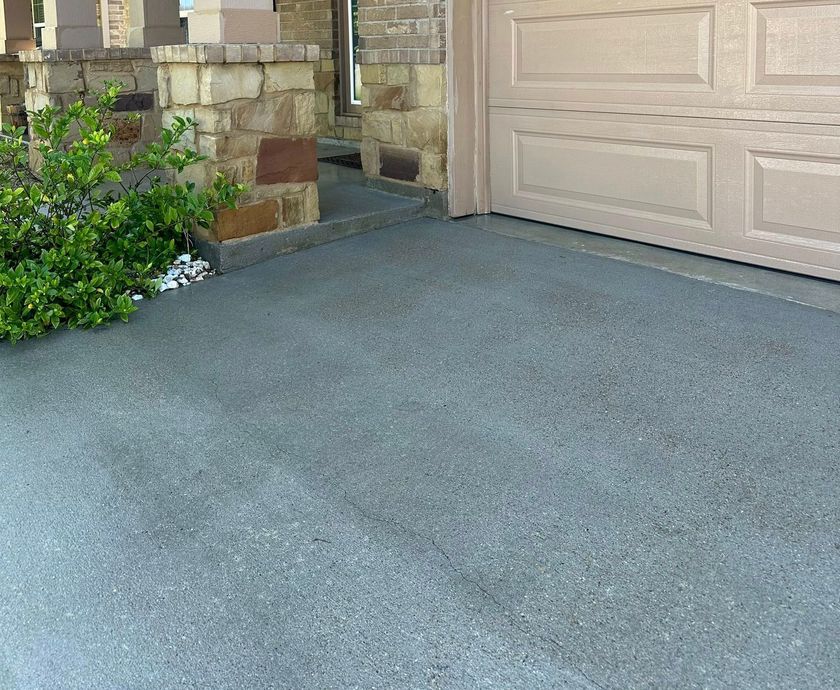 A concrete driveway with a garage door in the background