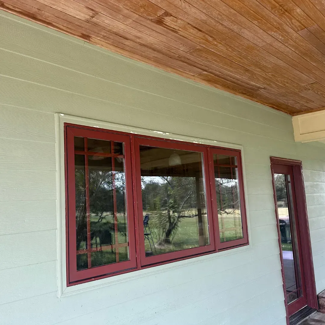 A white house with red windows and a wooden ceiling.