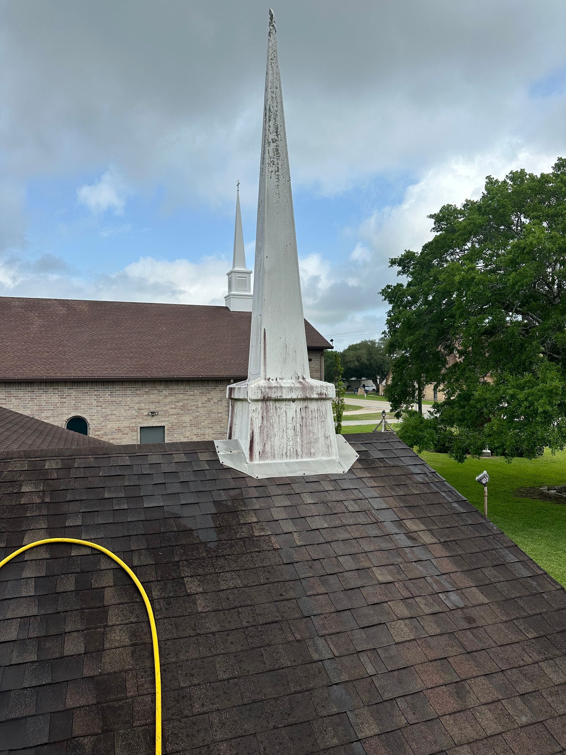 A church steeple is sitting on top of a roof with a hose attached to it.