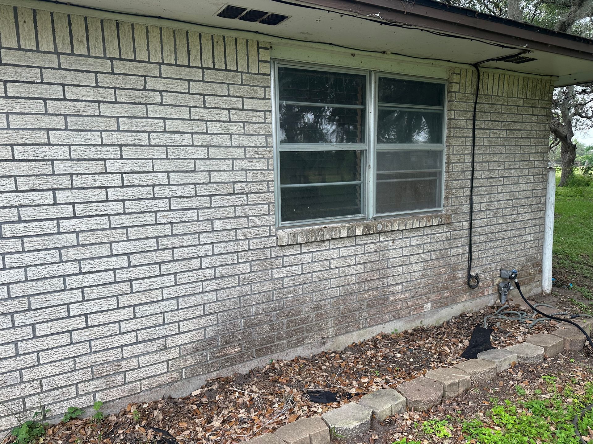 A white brick house with a window on the side of it.