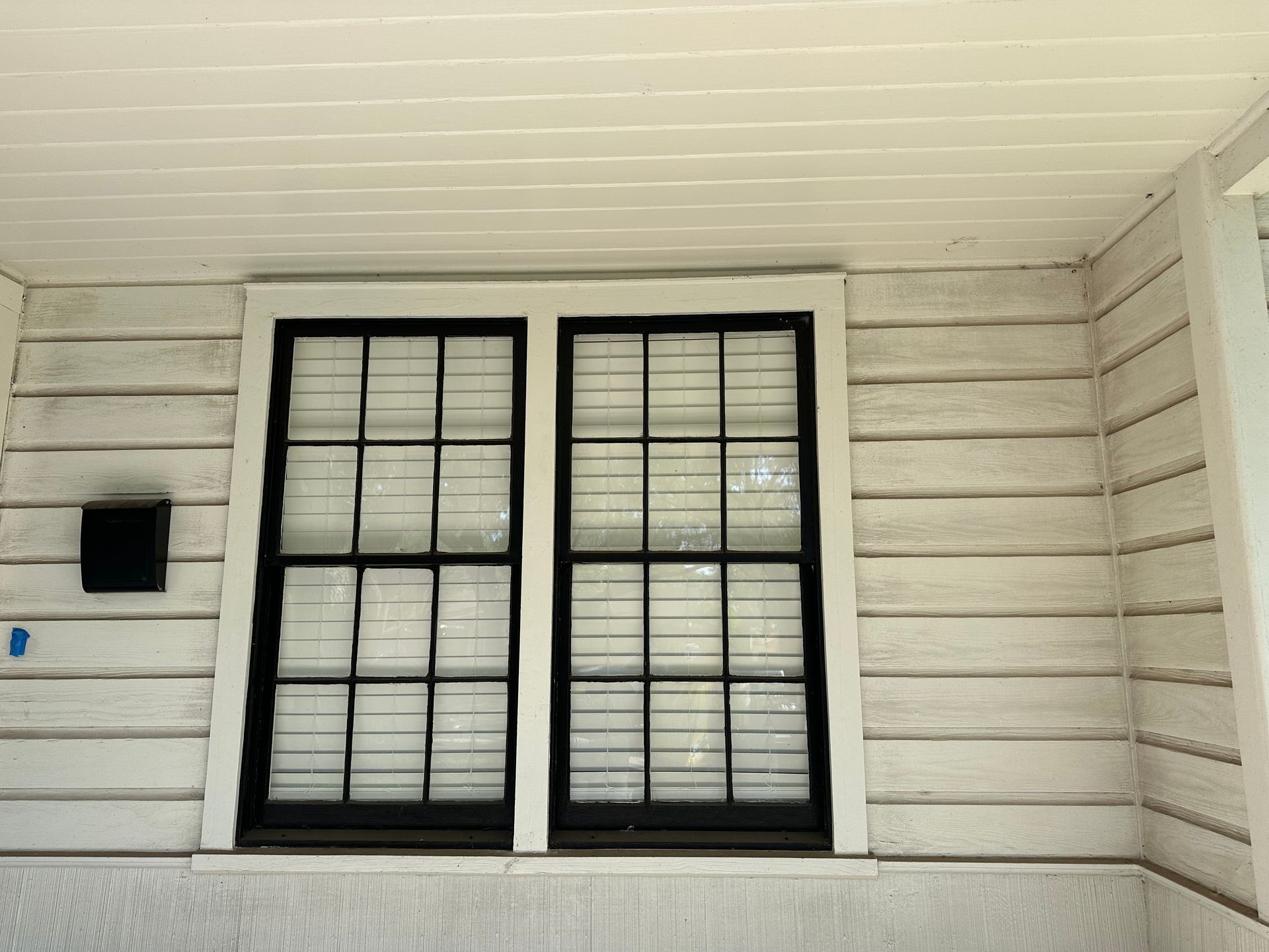 A white house with two windows and a mailbox on the side.