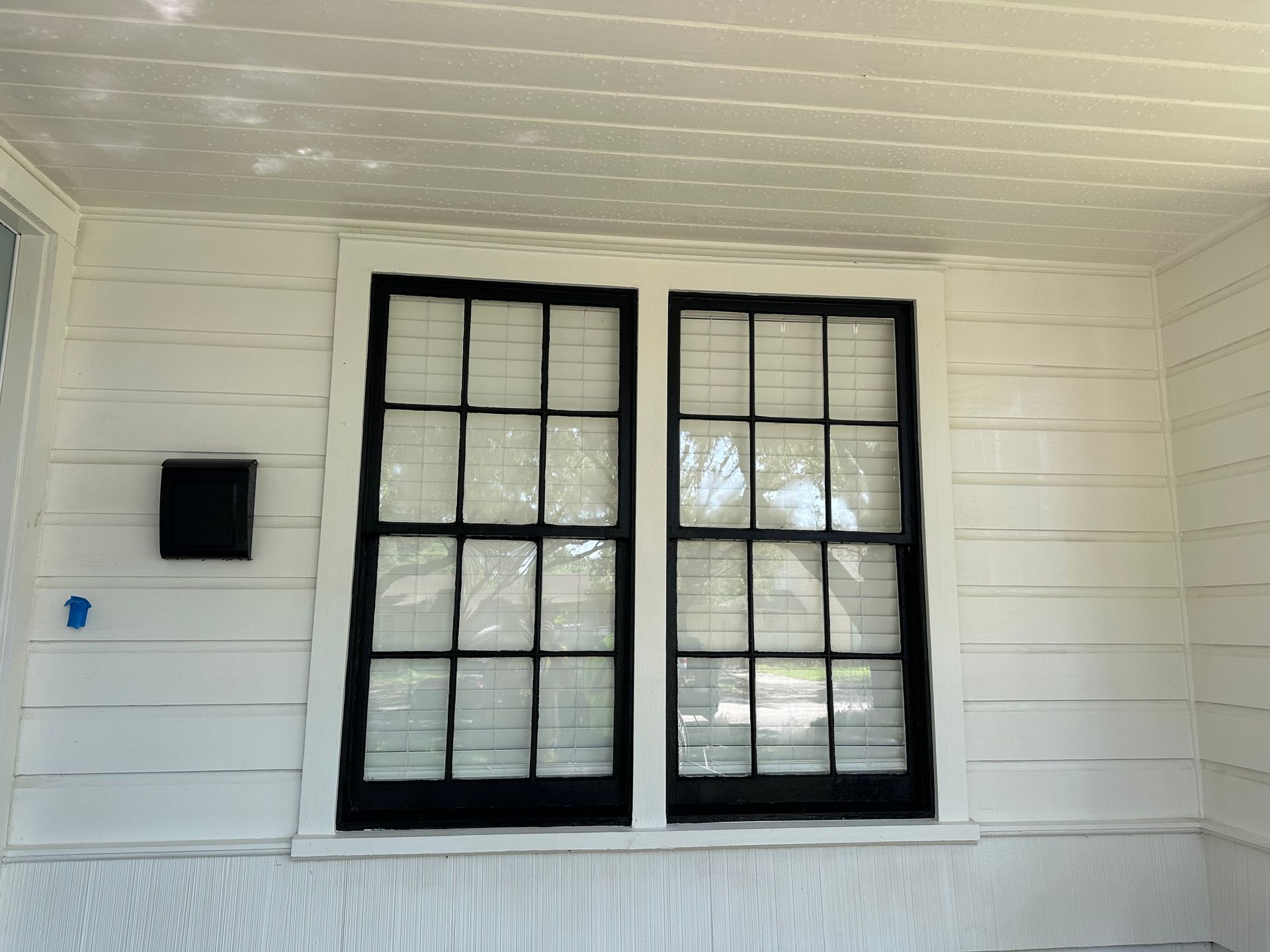 A white house with black windows and a mailbox.