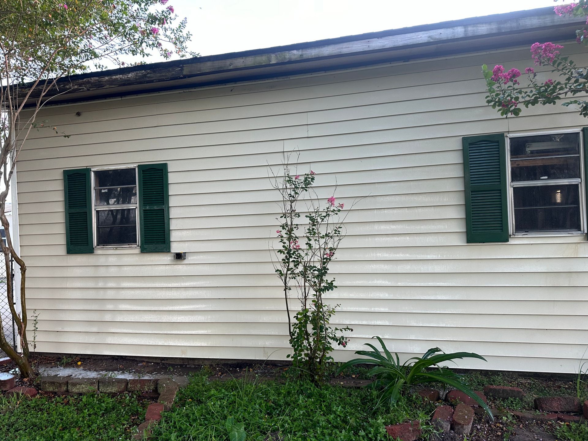 A white house with green shutters on the windows.
