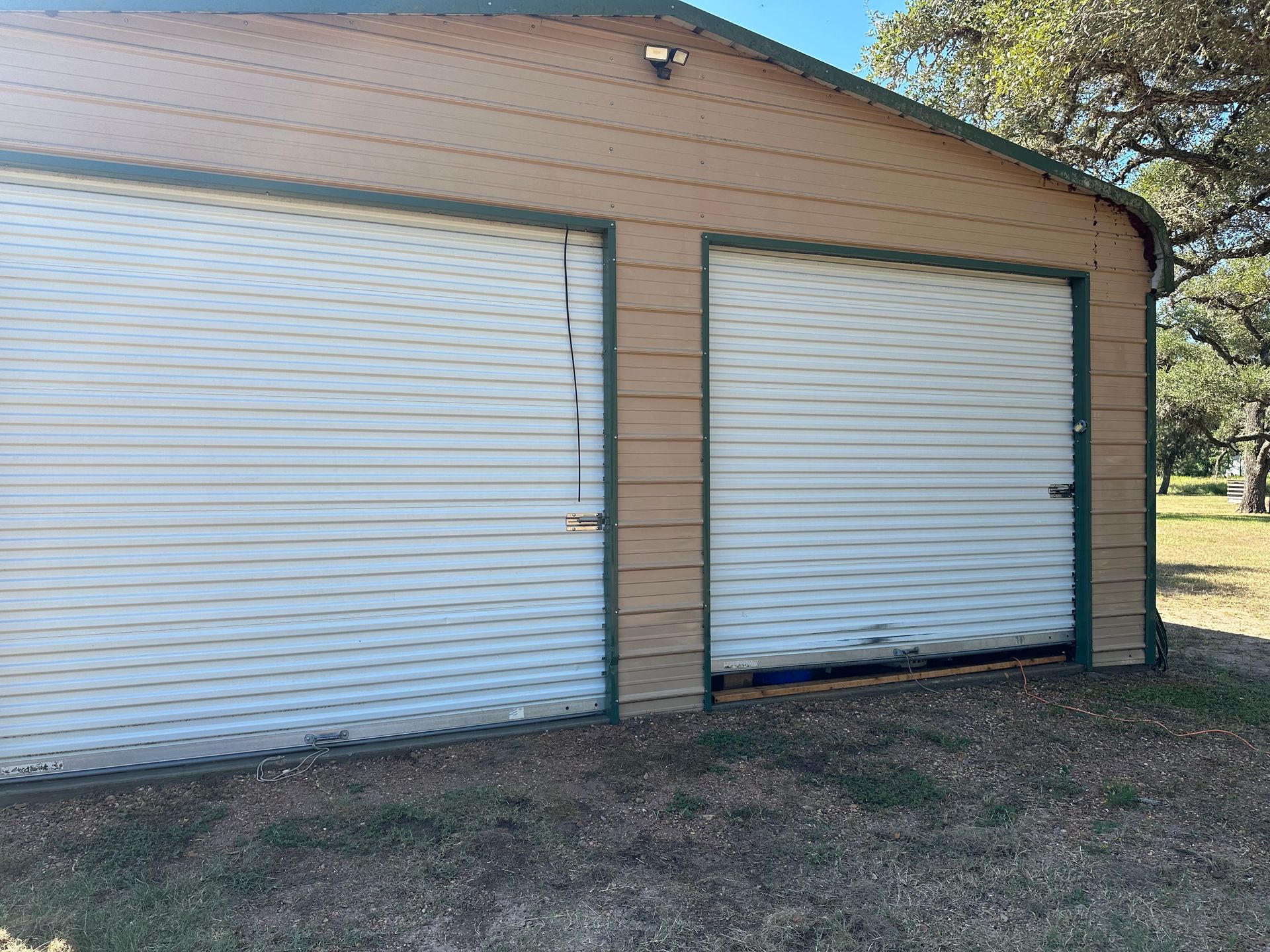 A garage with two white garage doors is sitting in the grass.