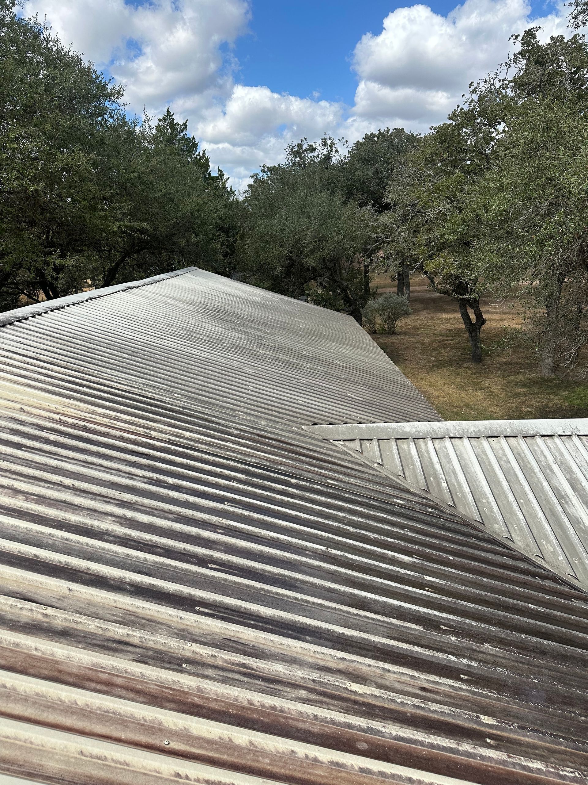 A roof with trees in the background and a blue sky in the background.