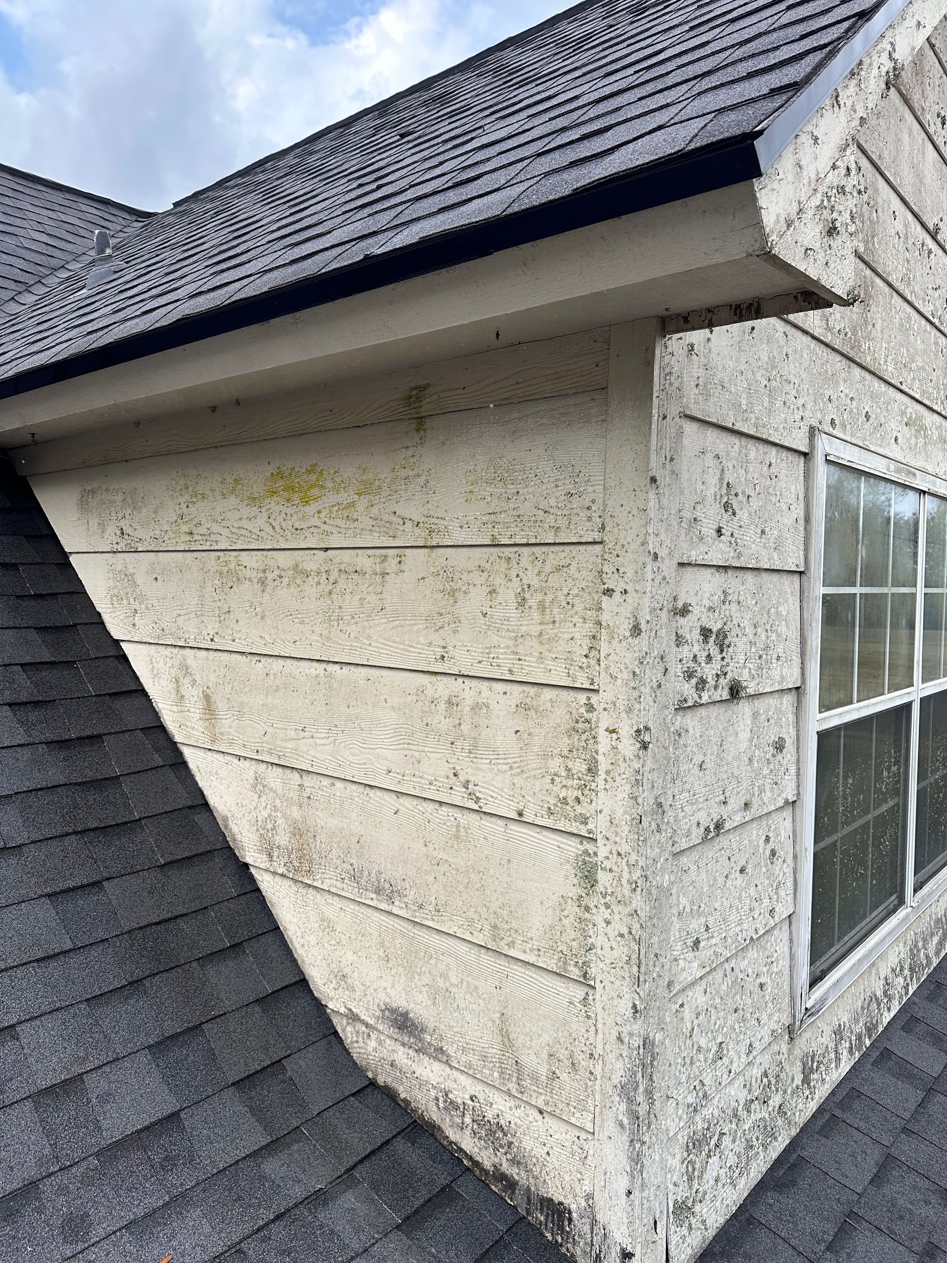 The side of a house with a roof and a window.