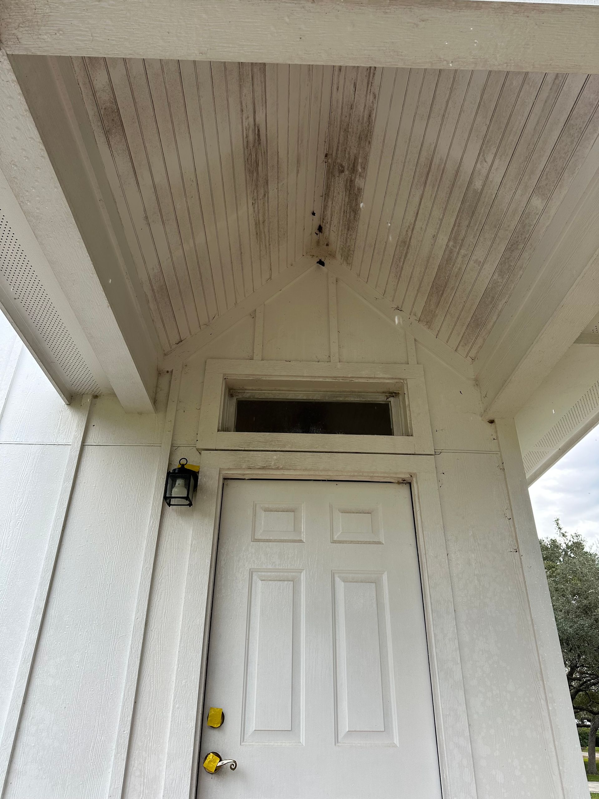 A white door with a yellow lock is on a white building.