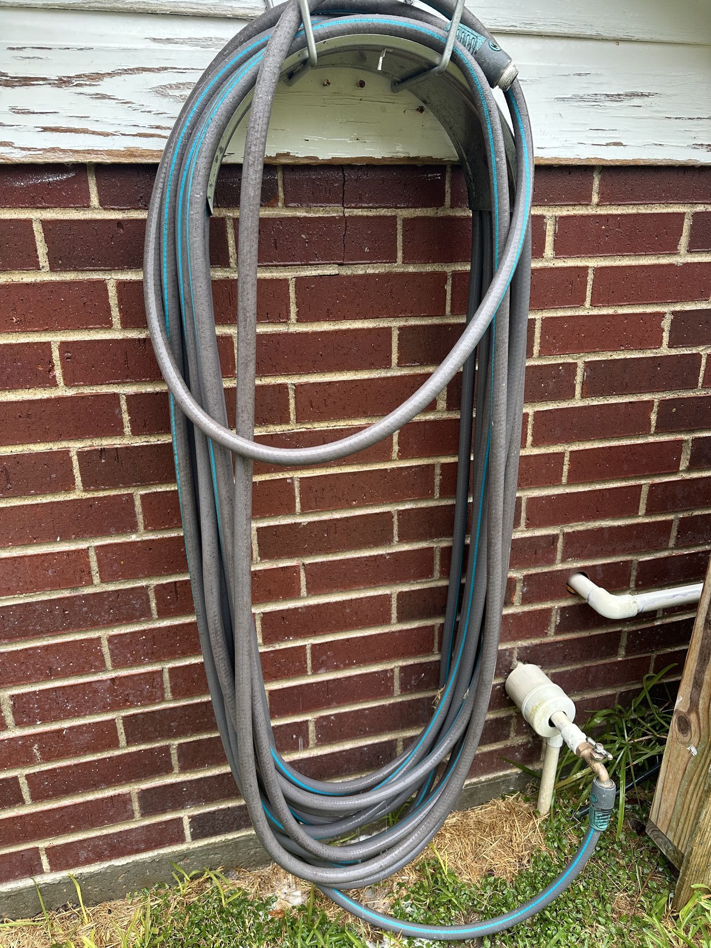 A hose is hanging on a brick wall.