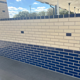 A white brick wall with blue tiles on the bottom