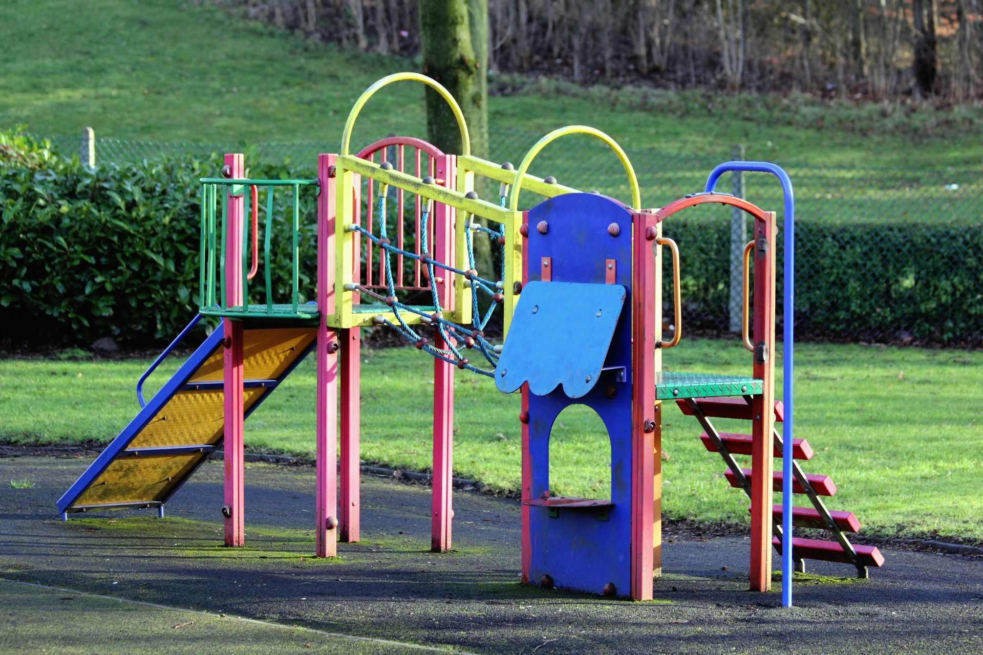 A colorful playground set in a park with grass in the background