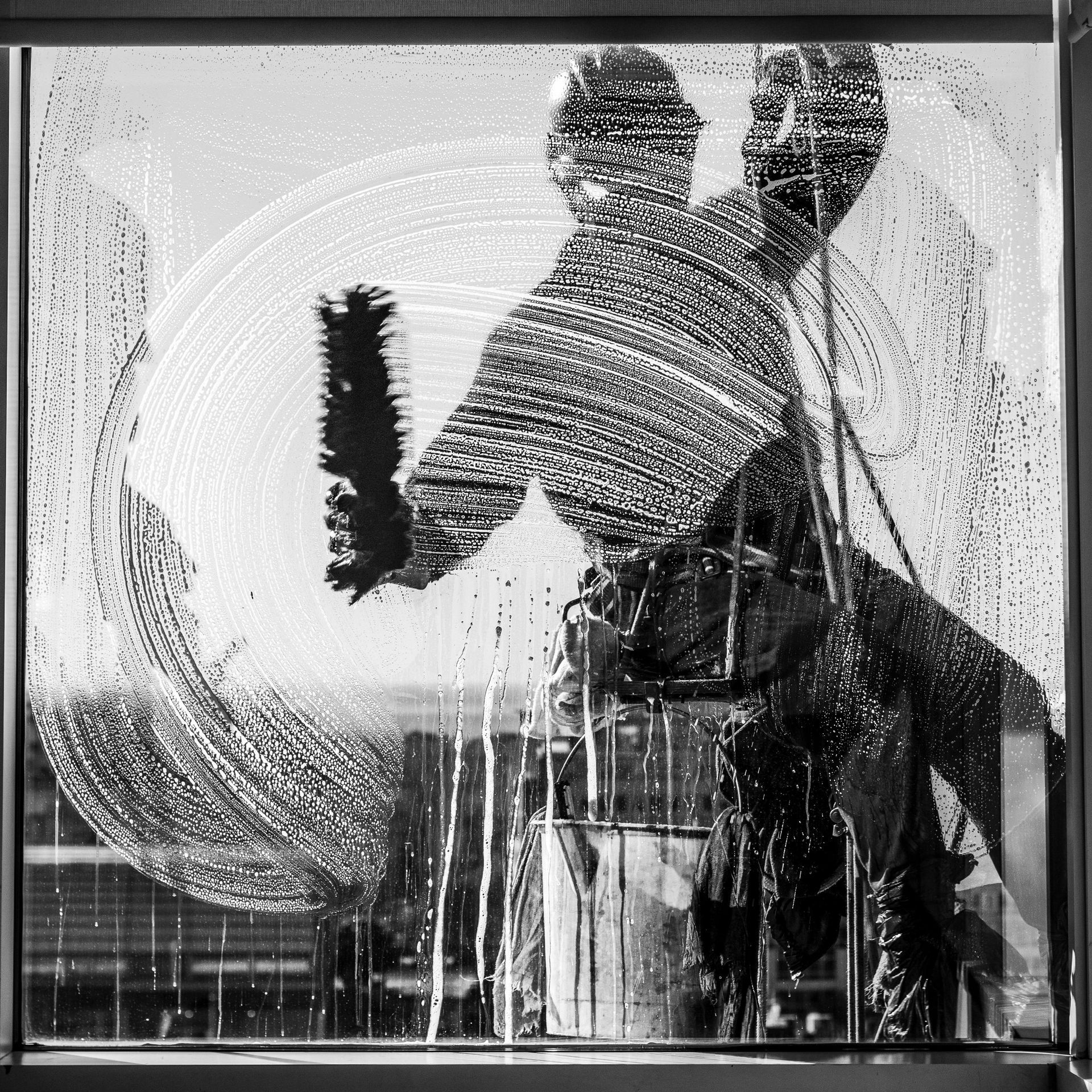A black and white photo of a person cleaning a window