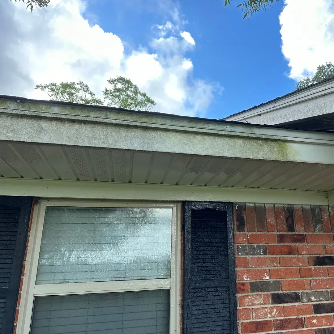 A brick house with a white roof and black shutters.