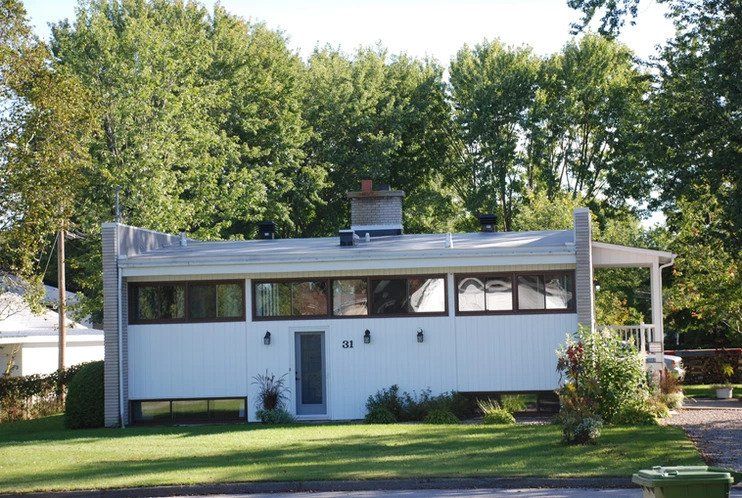 Une maison blanche avec une poubelle verte devant