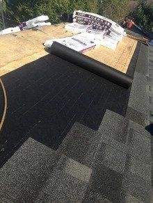 Un toit avec un rouleau de bardeaux dessus est en cours d'installation.