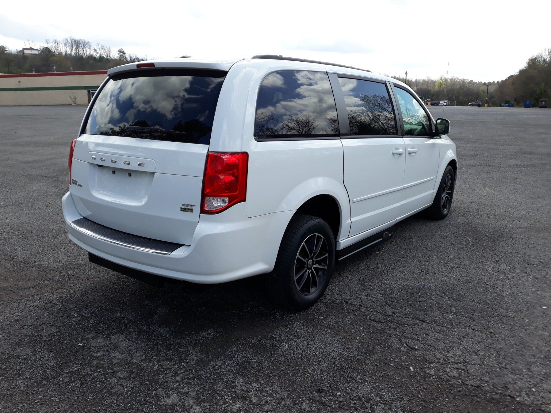 A white minivan is parked in a parking lot.