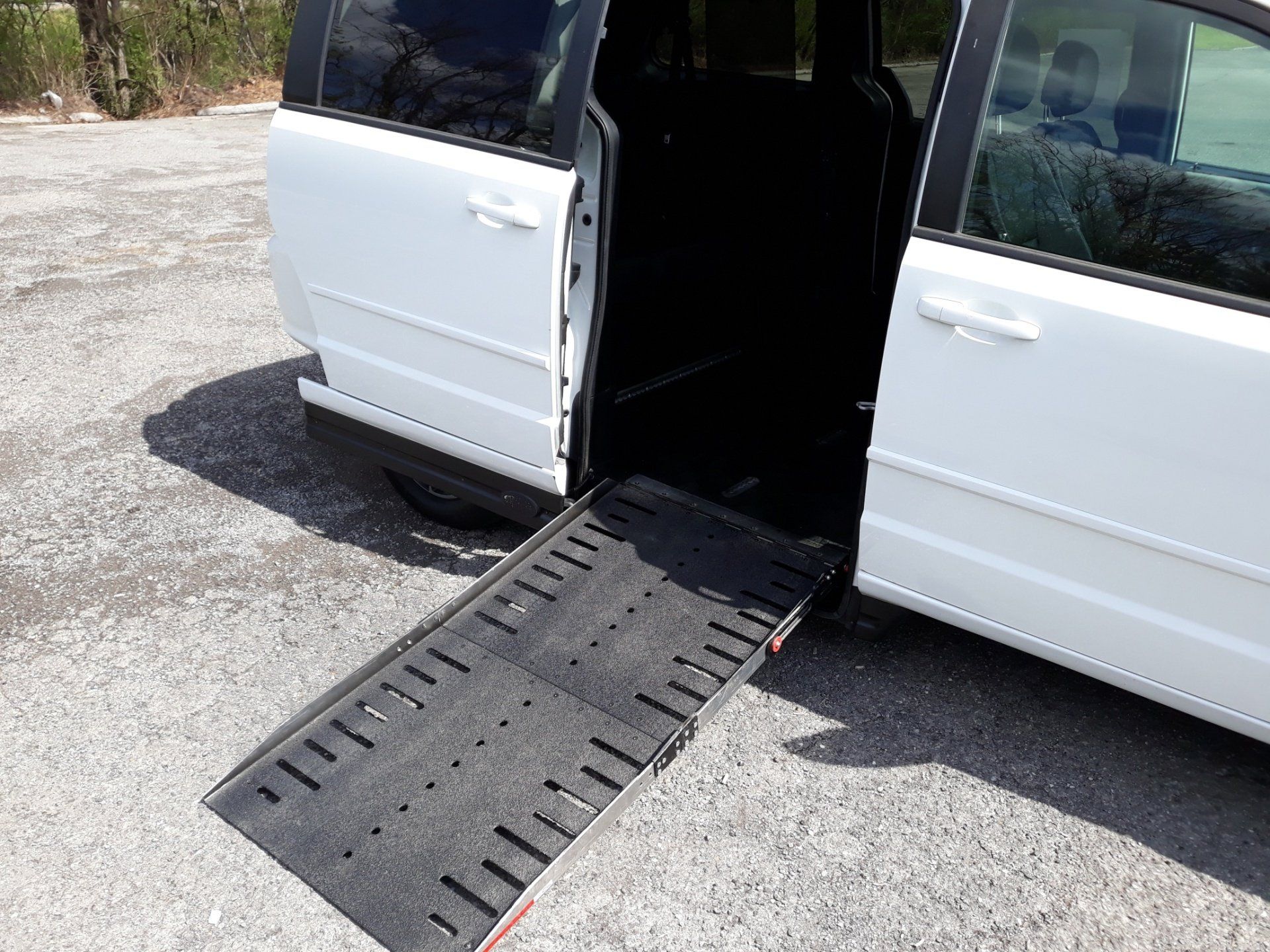 A white van with a handicap ramp is parked in a parking lot.