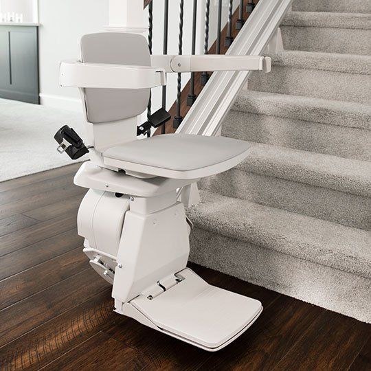 A white stair lift is sitting next to a set of stairs.