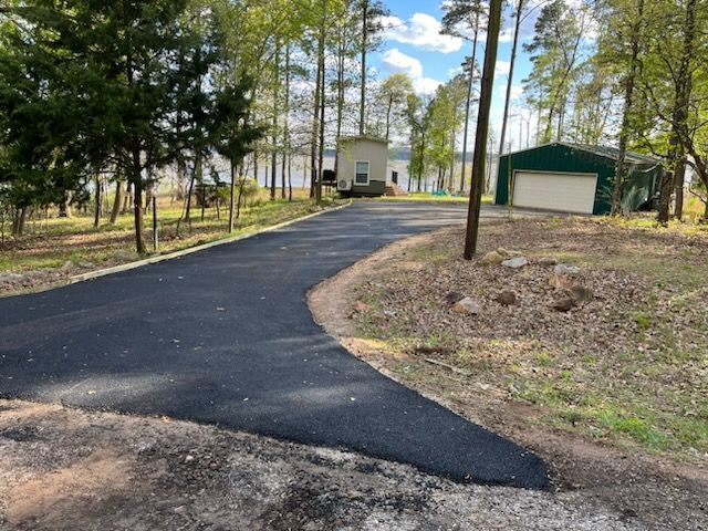 A newly paved driveway leading to a house in the woods