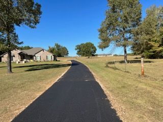 A road going through a grassy field to a house