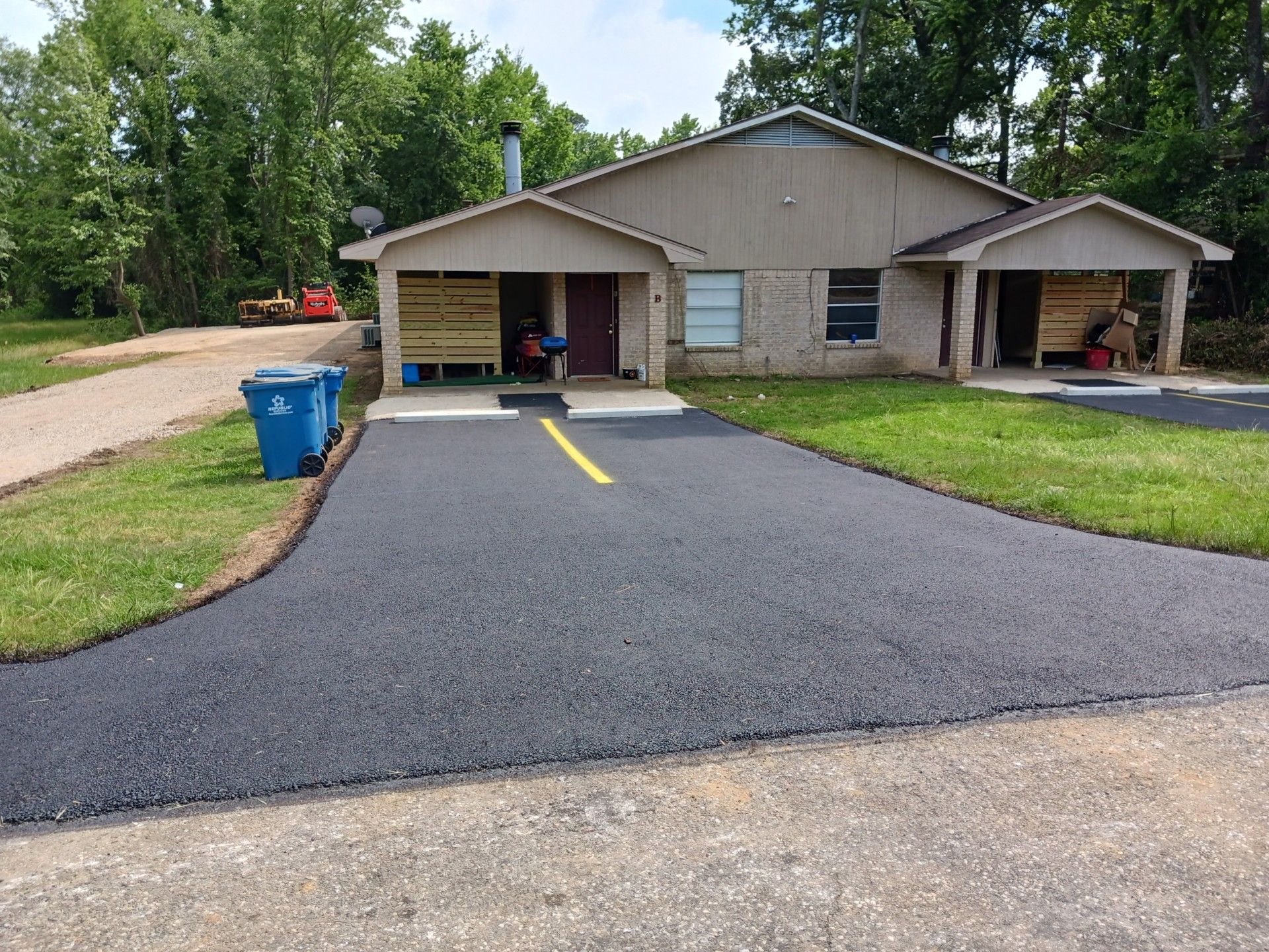 A house with a driveway and a blue trash can in front of it