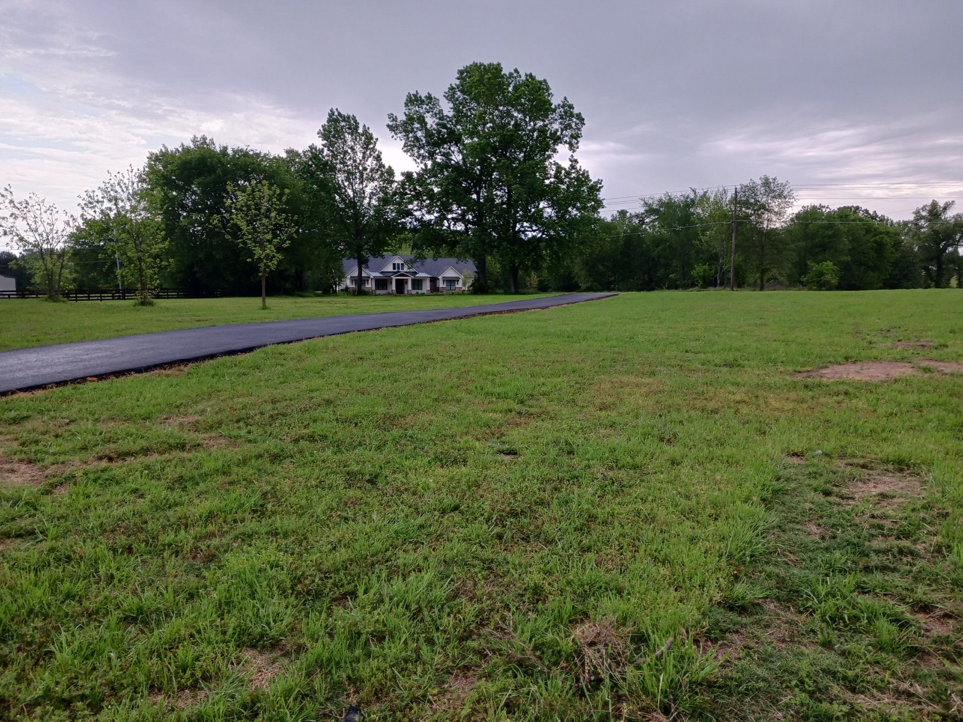 A large lush green field with a house in the background