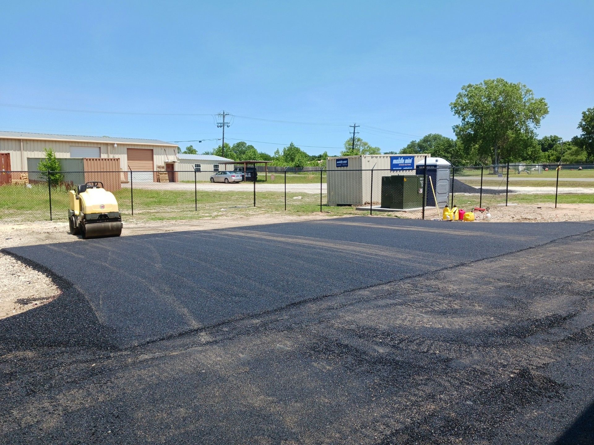 A roller is rolling asphalt in a parking lot