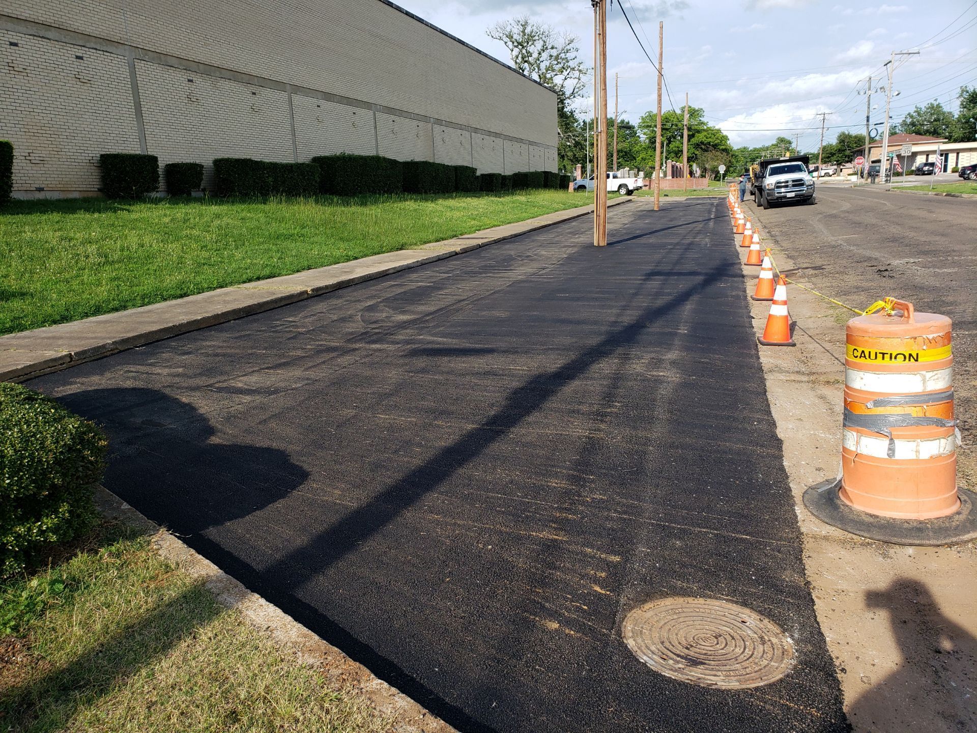A row of orange and white traffic cones are lined up on the side of a road.