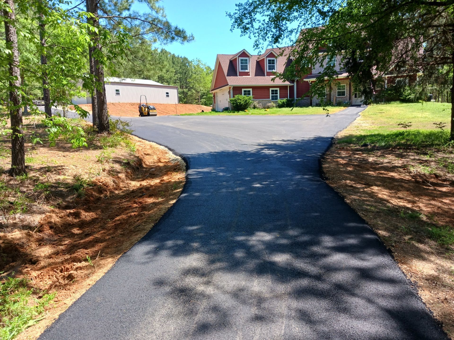 A driveway leading to a house surrounded by trees and grass