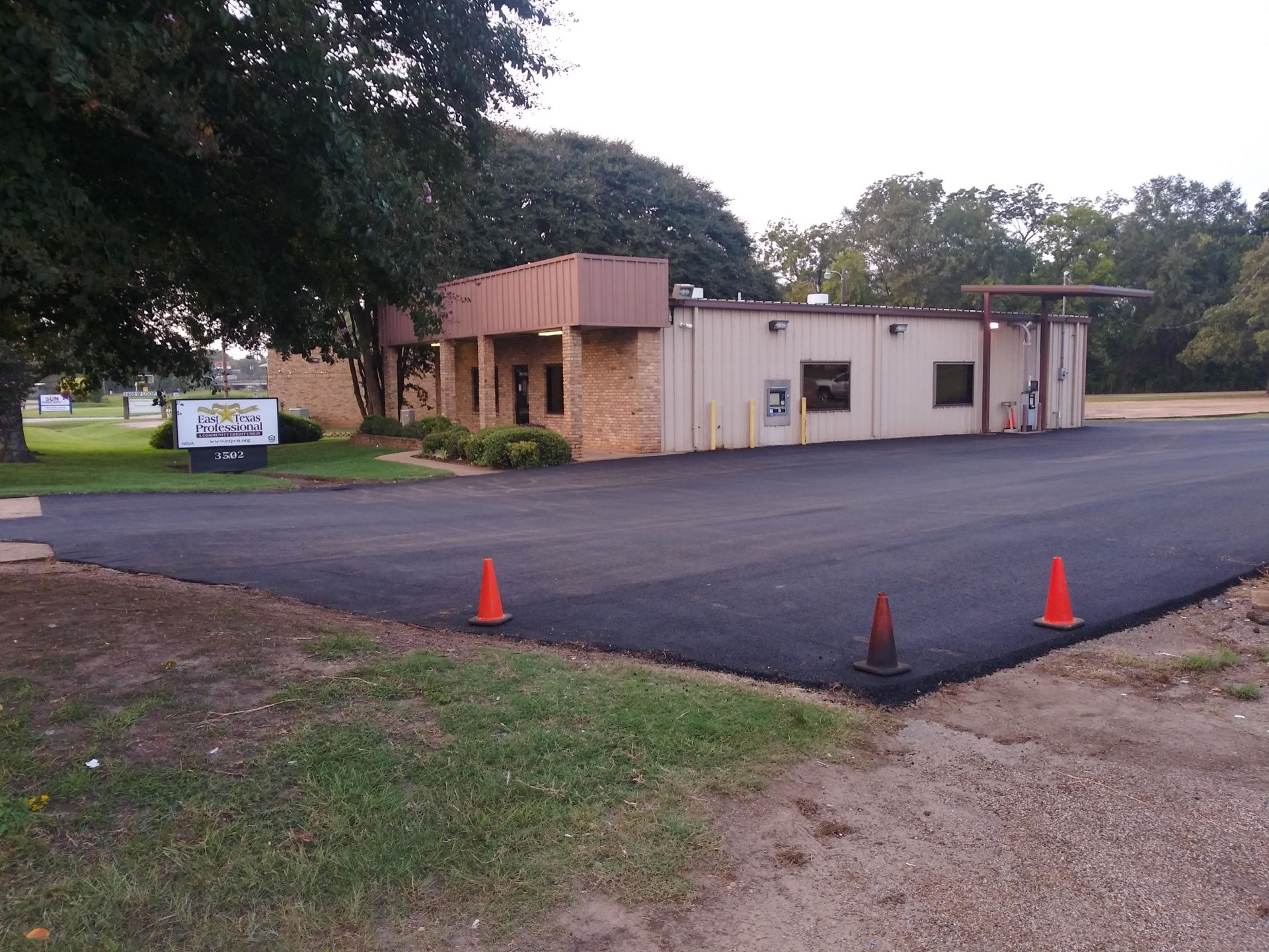 A parking lot with two orange cones in front of a building