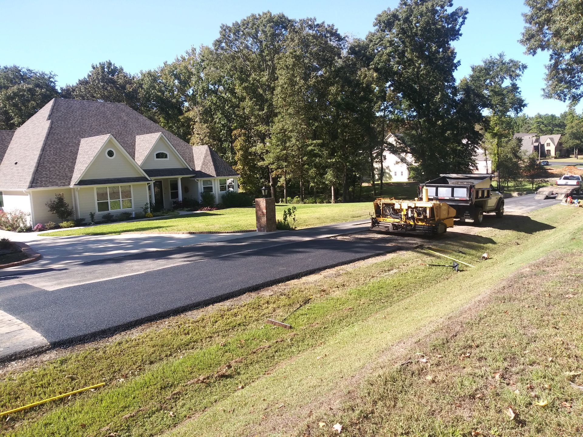 A yellow truck is parked on the side of the road in front of a house