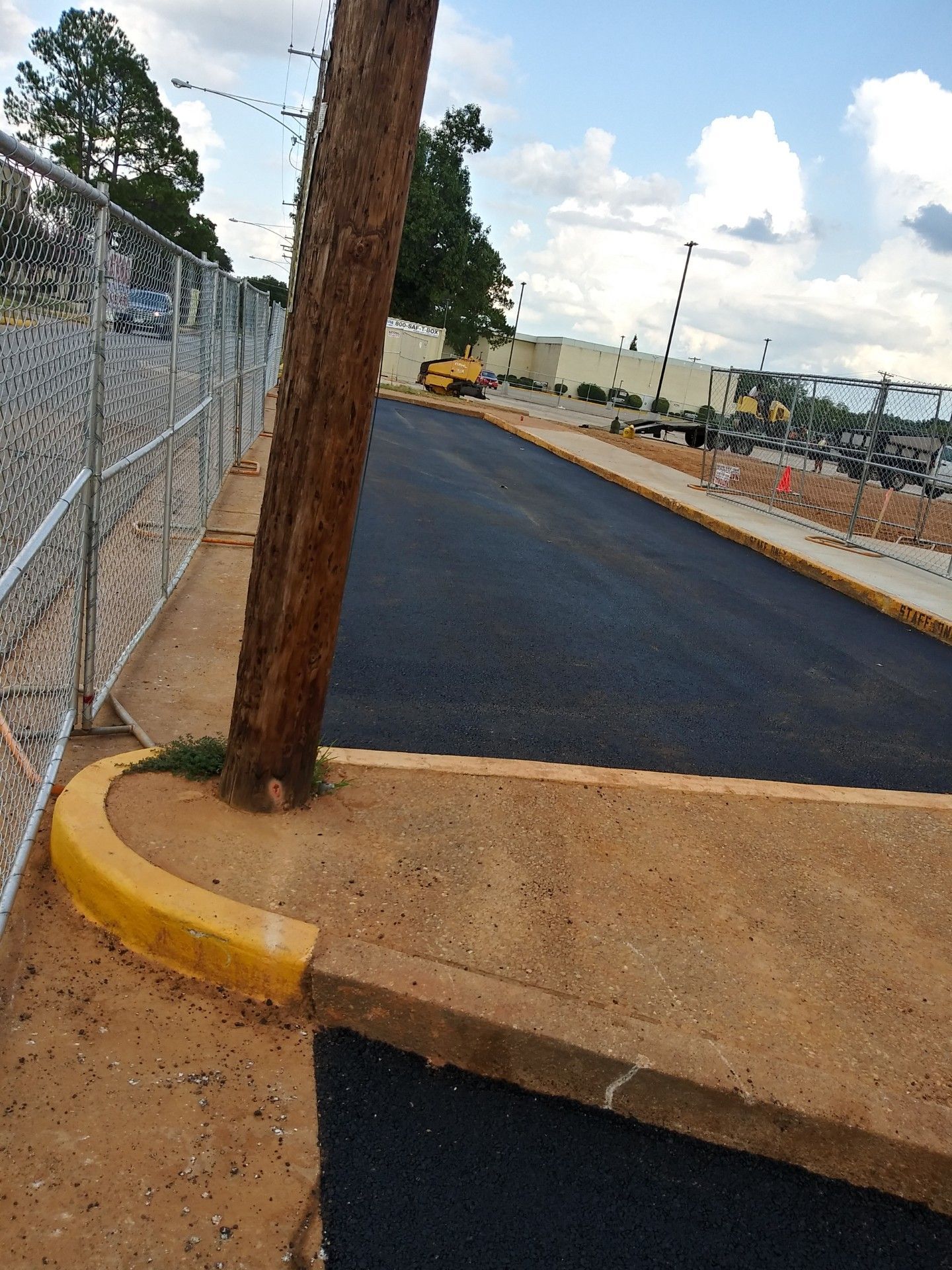 A telephone pole is sitting on the side of a road.