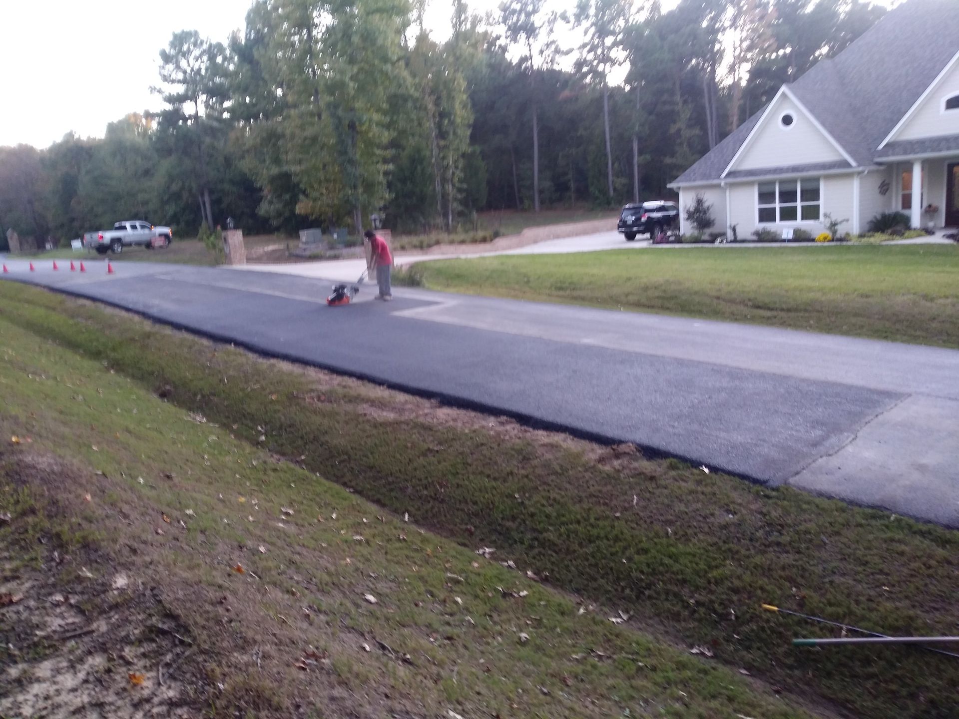 A man is painting a driveway in front of a house