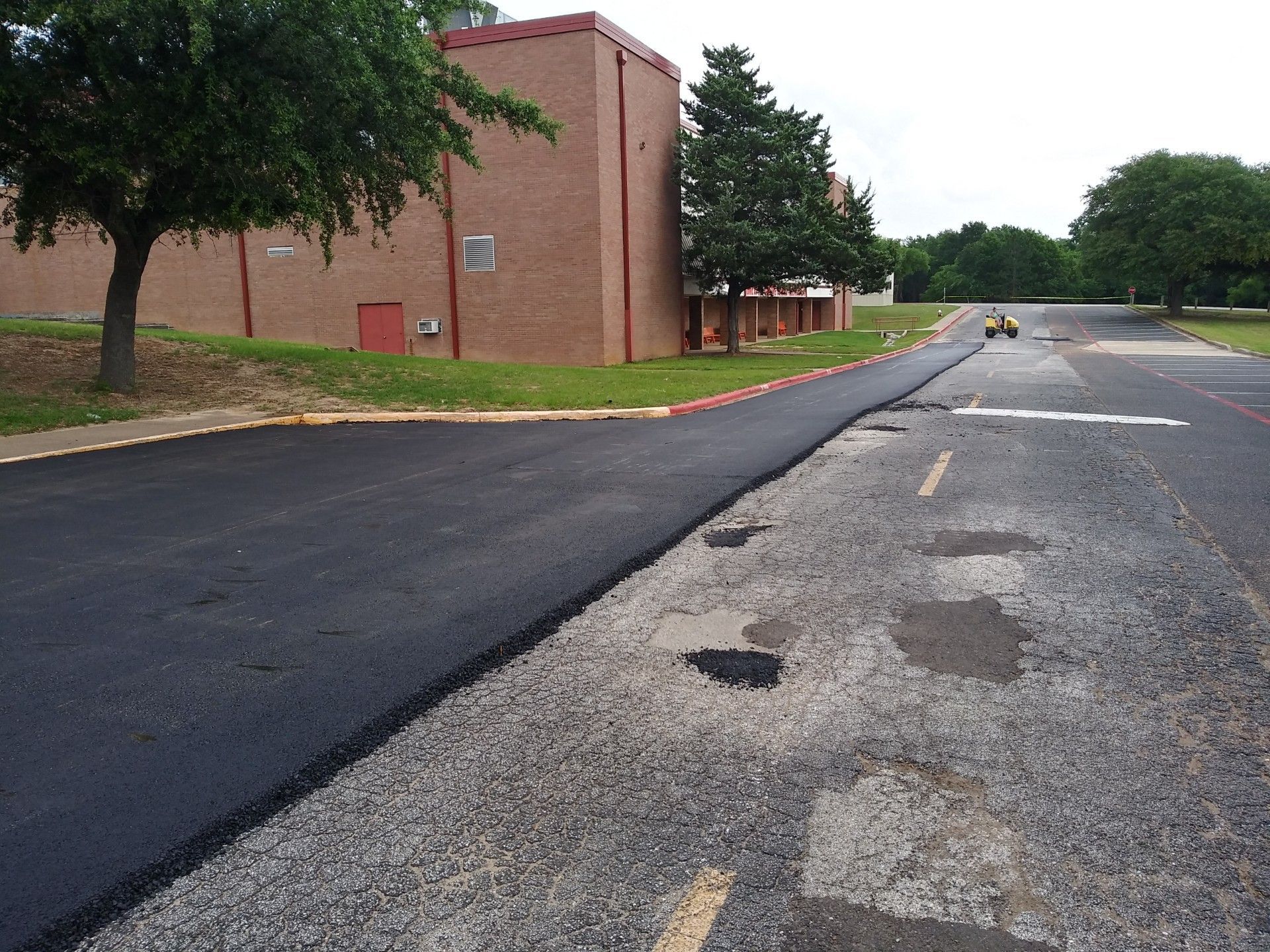 A newly paved road with a brick building in the background