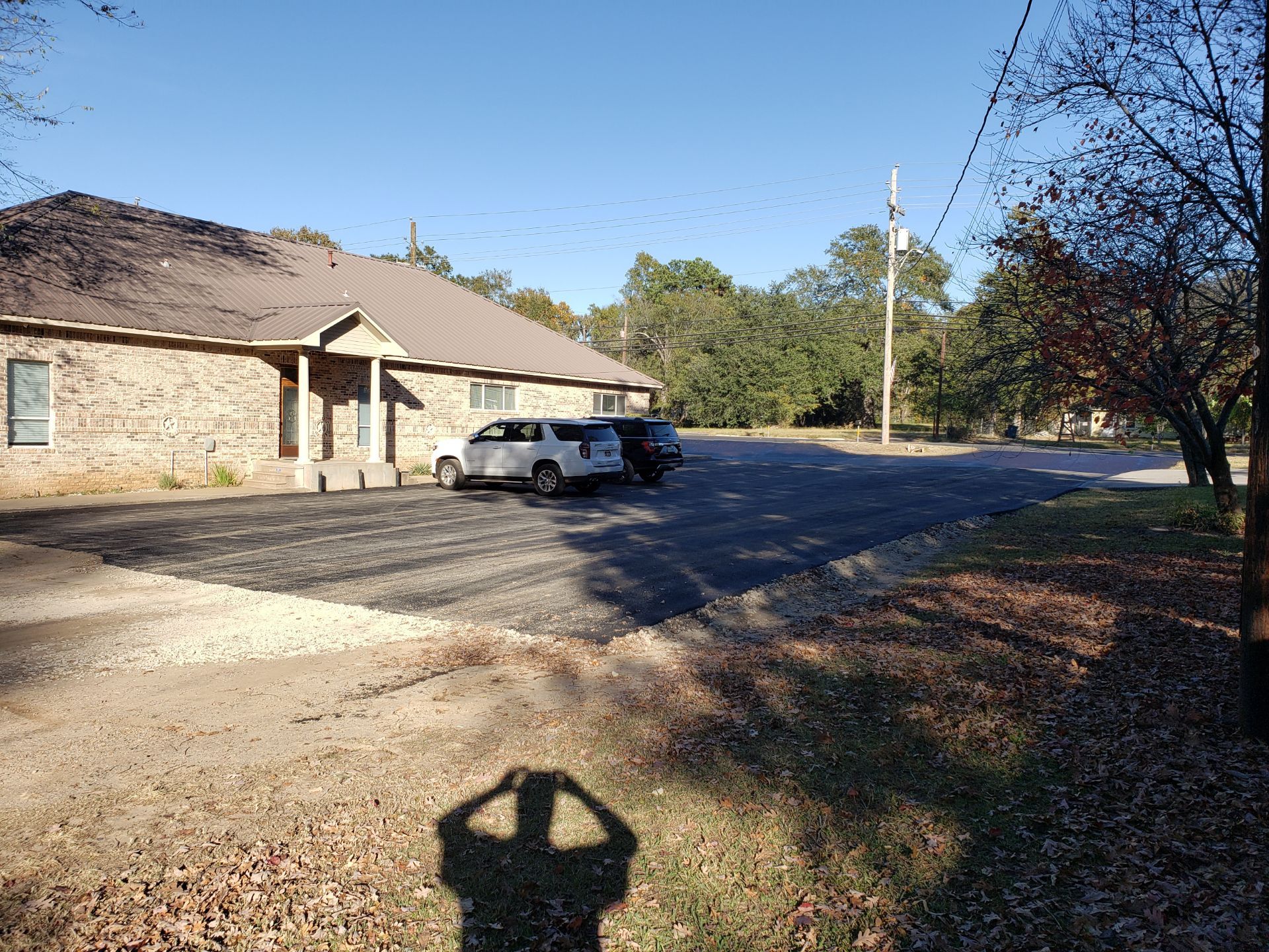 A shadow of a person is cast on the ground in front of a building.